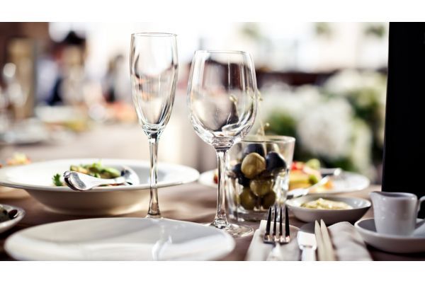 Fine dining table with plated dishes, wine glasses, and olives