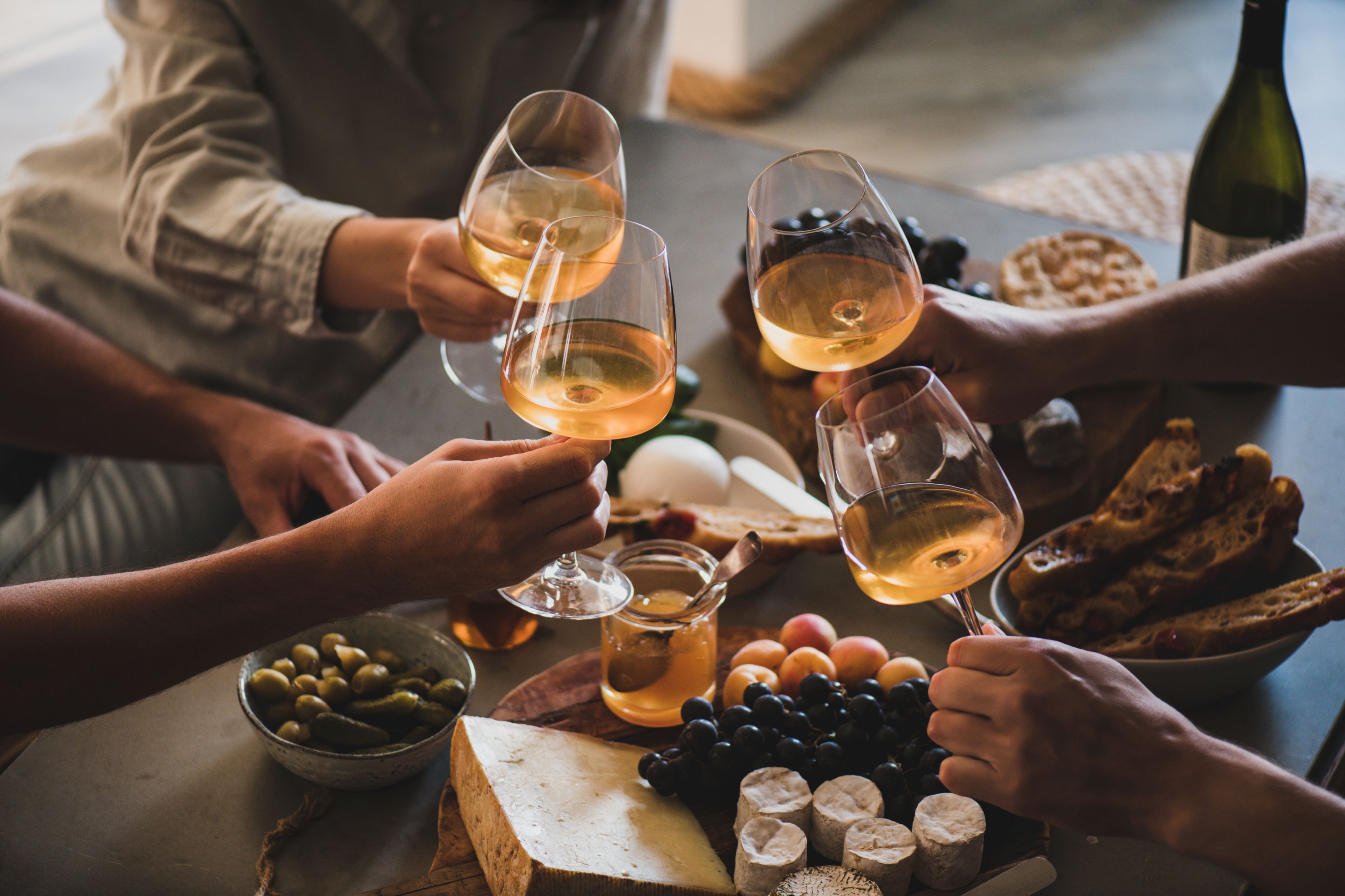 Wine and cheese arrangement with glasses on a dining table.