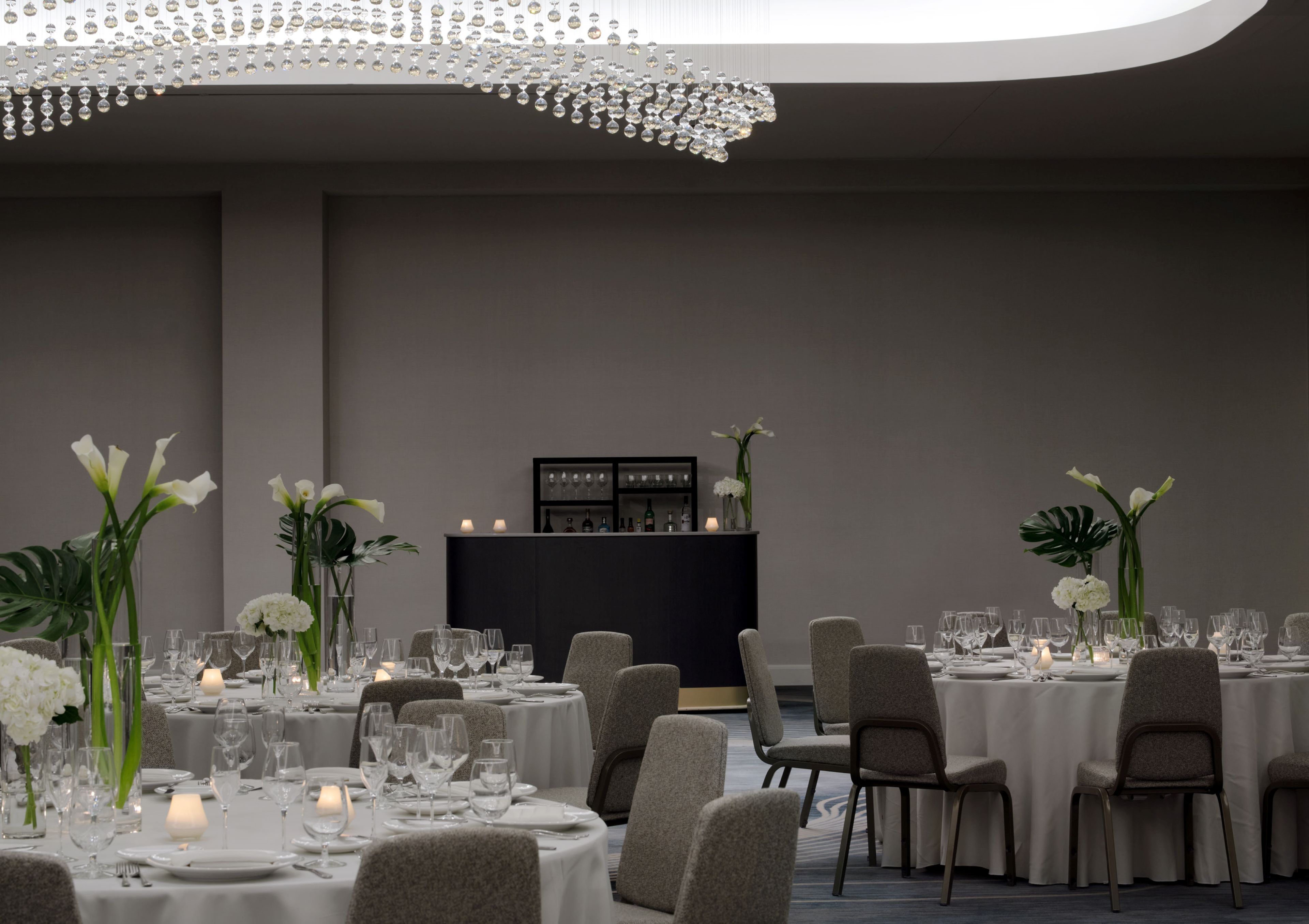Elegant banquet space with round tables, floral centerpieces, and chandelier lighting.
