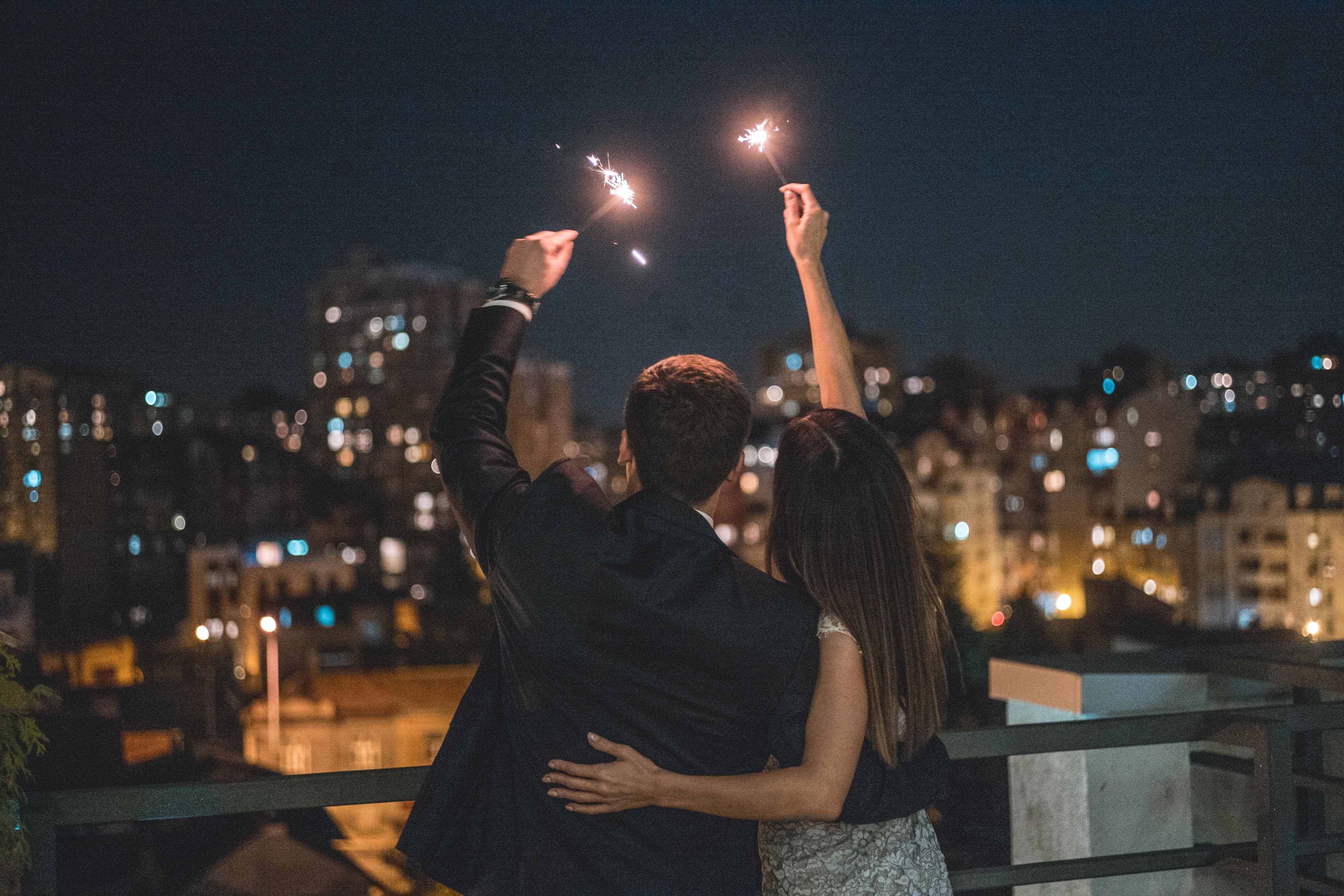 couple on rooftop holding firecrackers