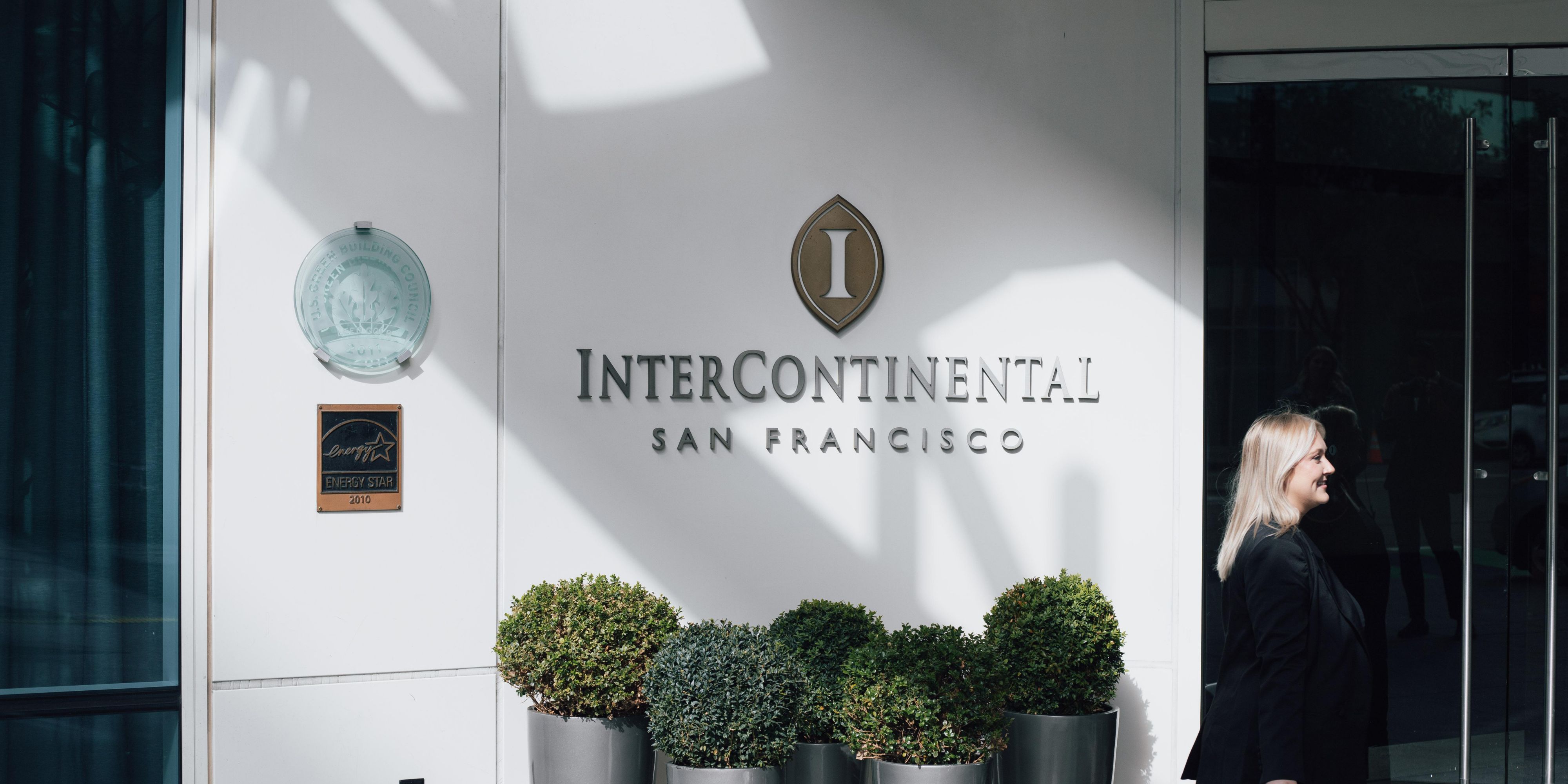 Guest walking in front of InterContinental San Francisco sign on exterior of hotel.