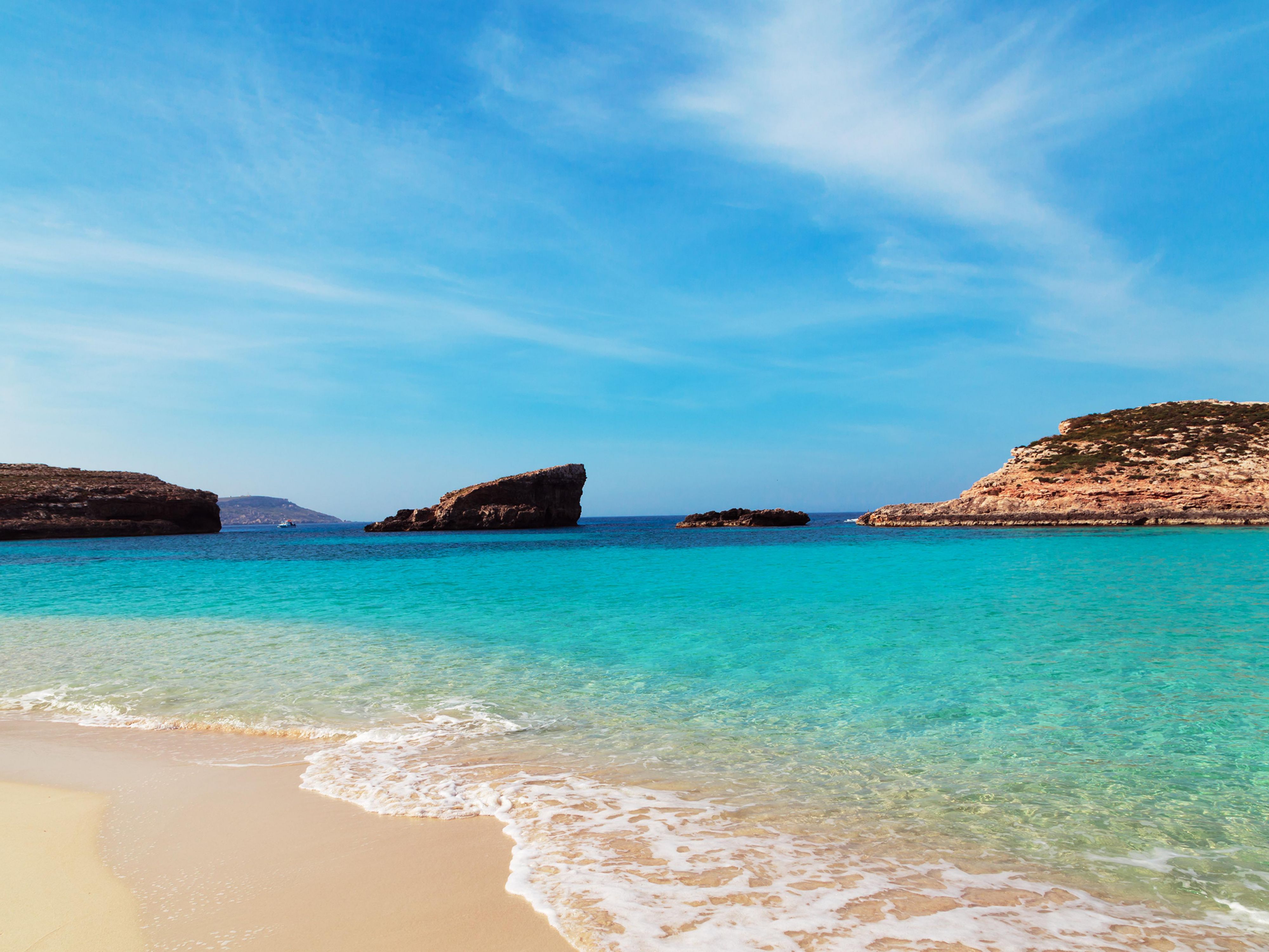 Clear turquoise water and sandy beach at Comimo Blue Lagoon