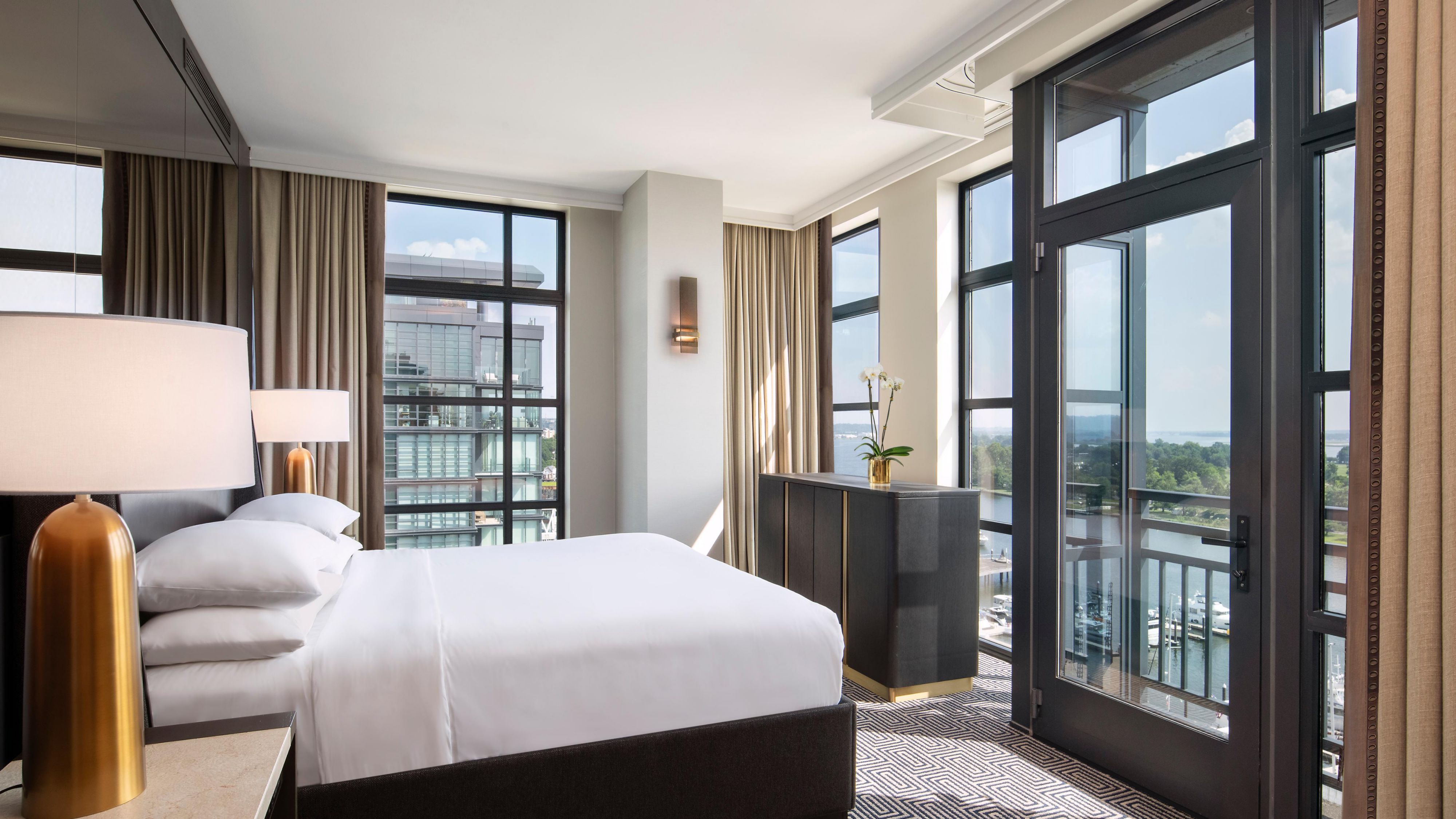 Corner king bedroom with gold-shaded lamp and marina views.