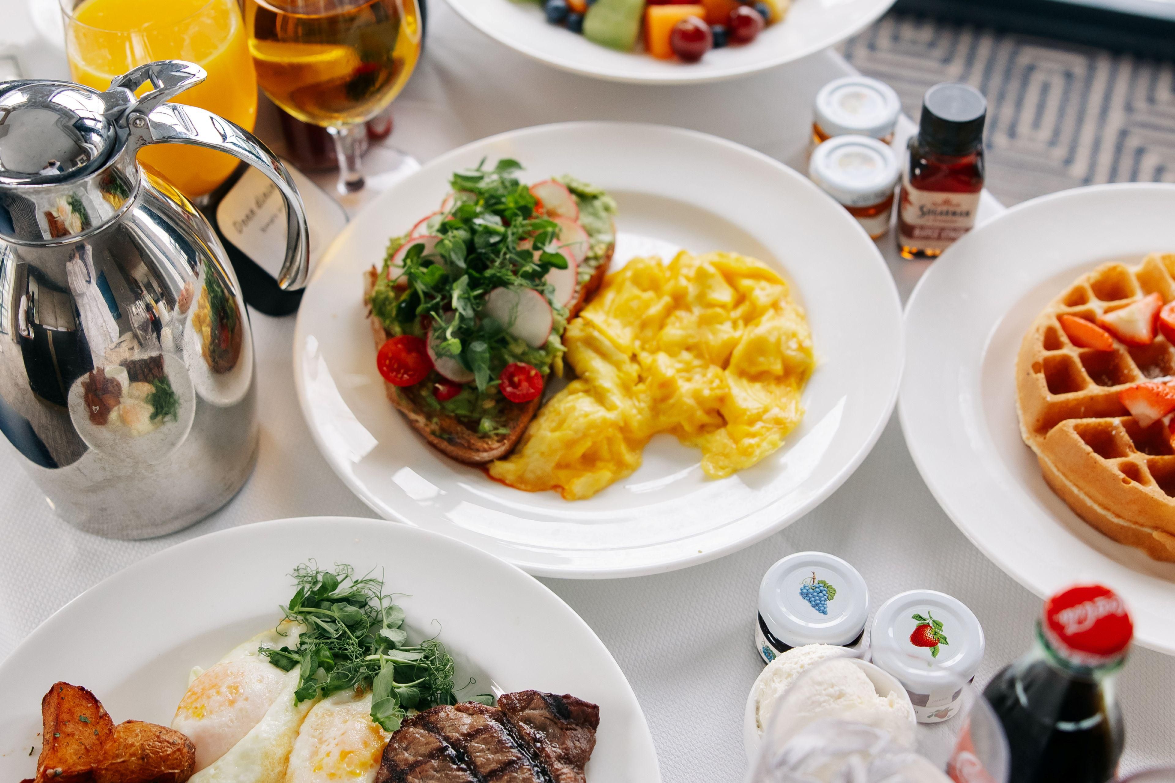 Lavish breakfast spread with fruit, avocado toast, and waffles