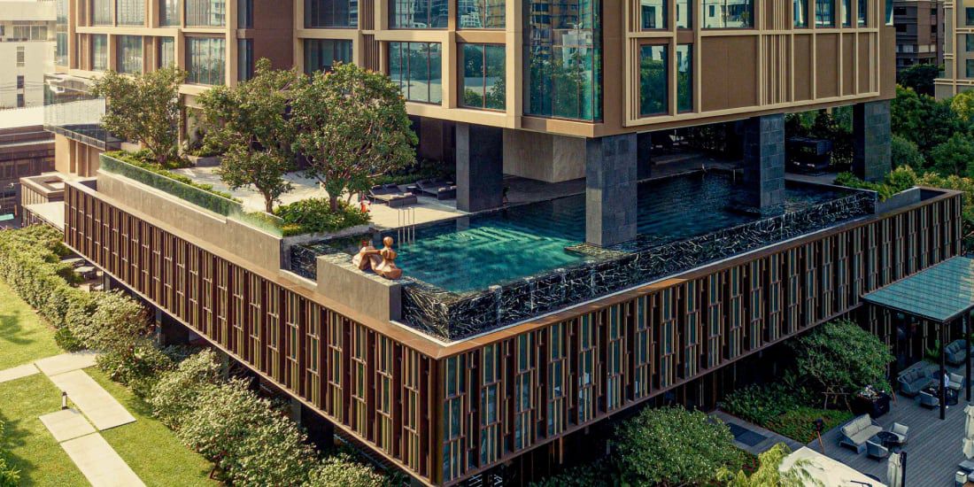 A hotel infinity pool surrounded by lush landscaping.