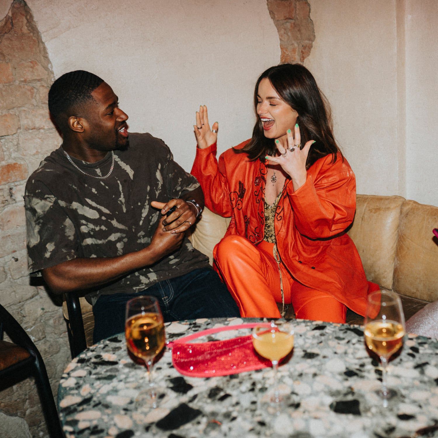 A man and woman in an animated conversation over cocktails.
