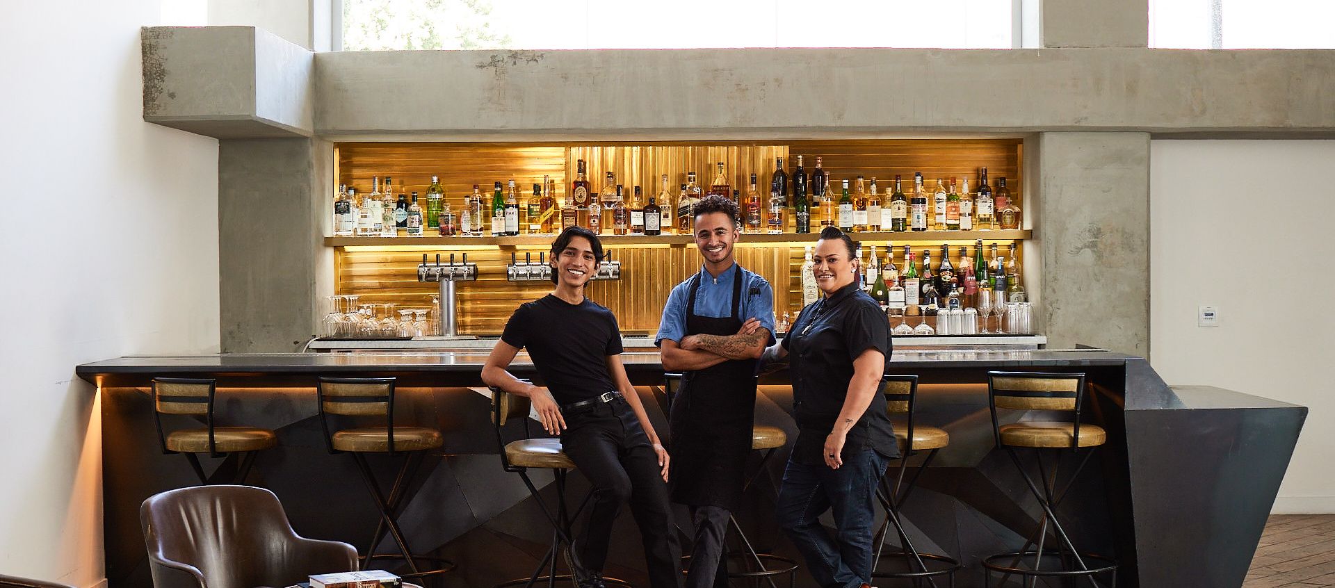 three employees smiling in a hotel lobby bar