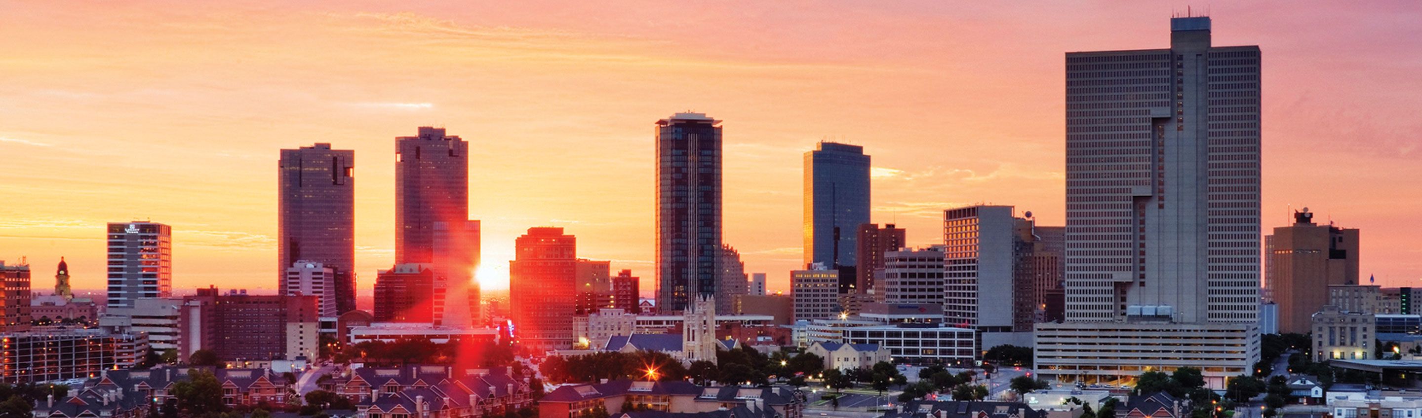 aireal view of Fort Worth city scape with sun setting behind skyscrapers 