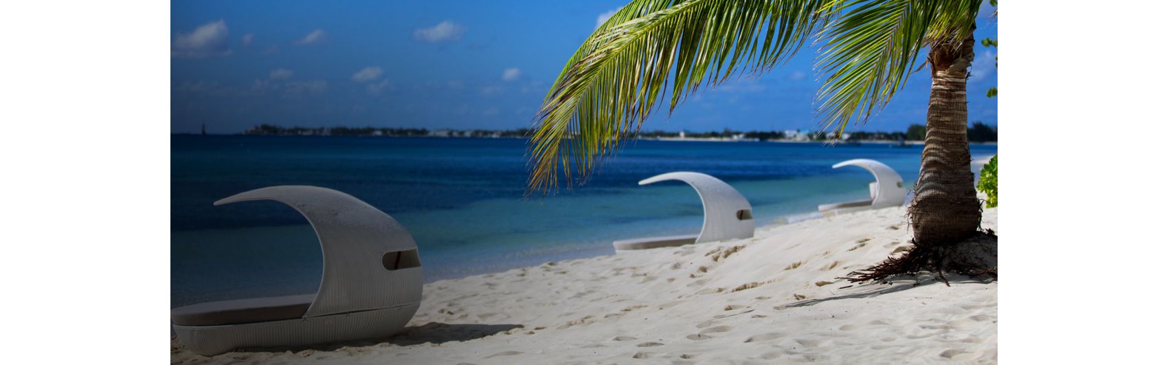 white sand beach lined with cabanas facing turquoise blue ocean