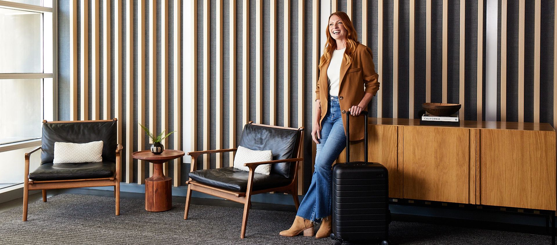woman with suitcase smiling in hotel lobby