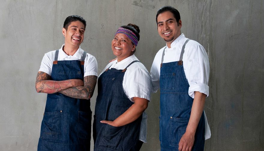 three chefs in white shirts and denim aprons