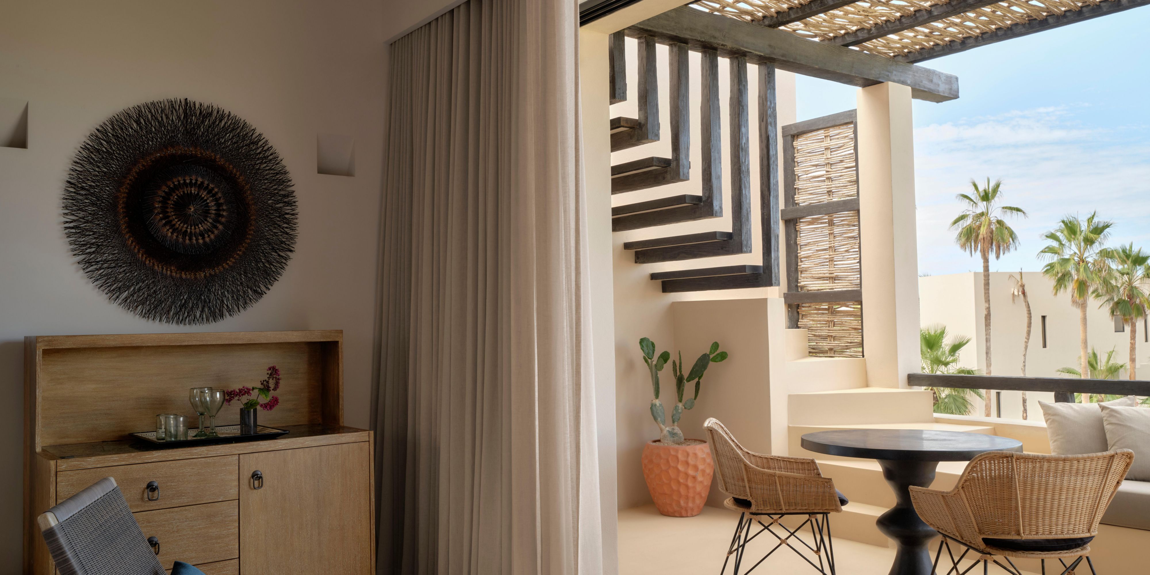 The seating area opens to a shaded terrace with woven furniture.