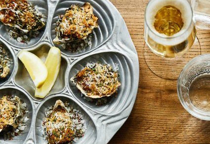 silver plate of baked oysters with glass of white wine
