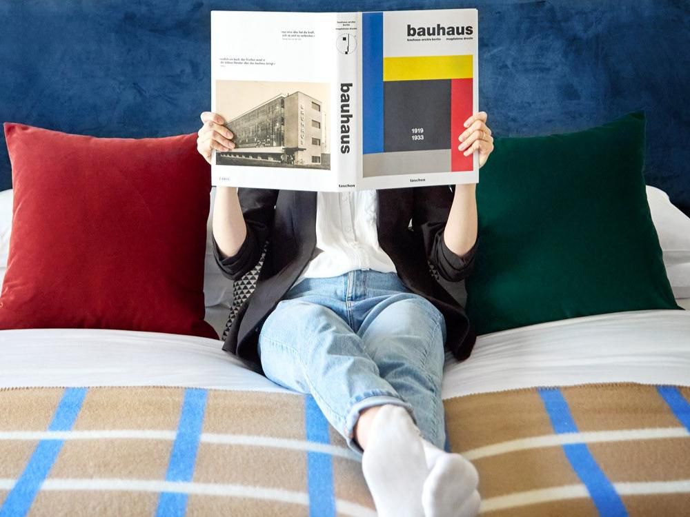 A person reading a magazine whilst laying down on a hotel made bed