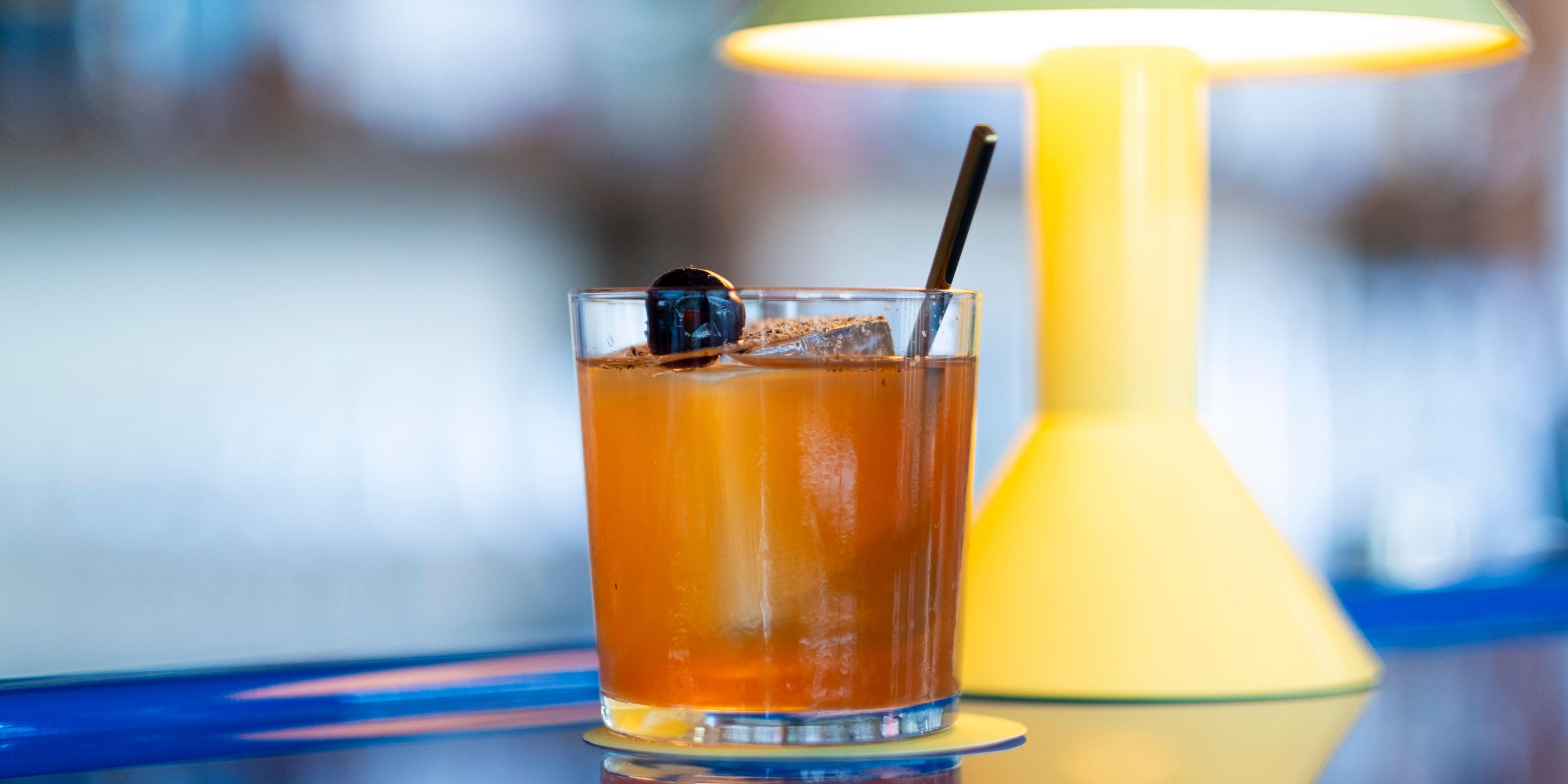 ein orangefarbener Cocktail auf einer elektrisierenden blauen Bar