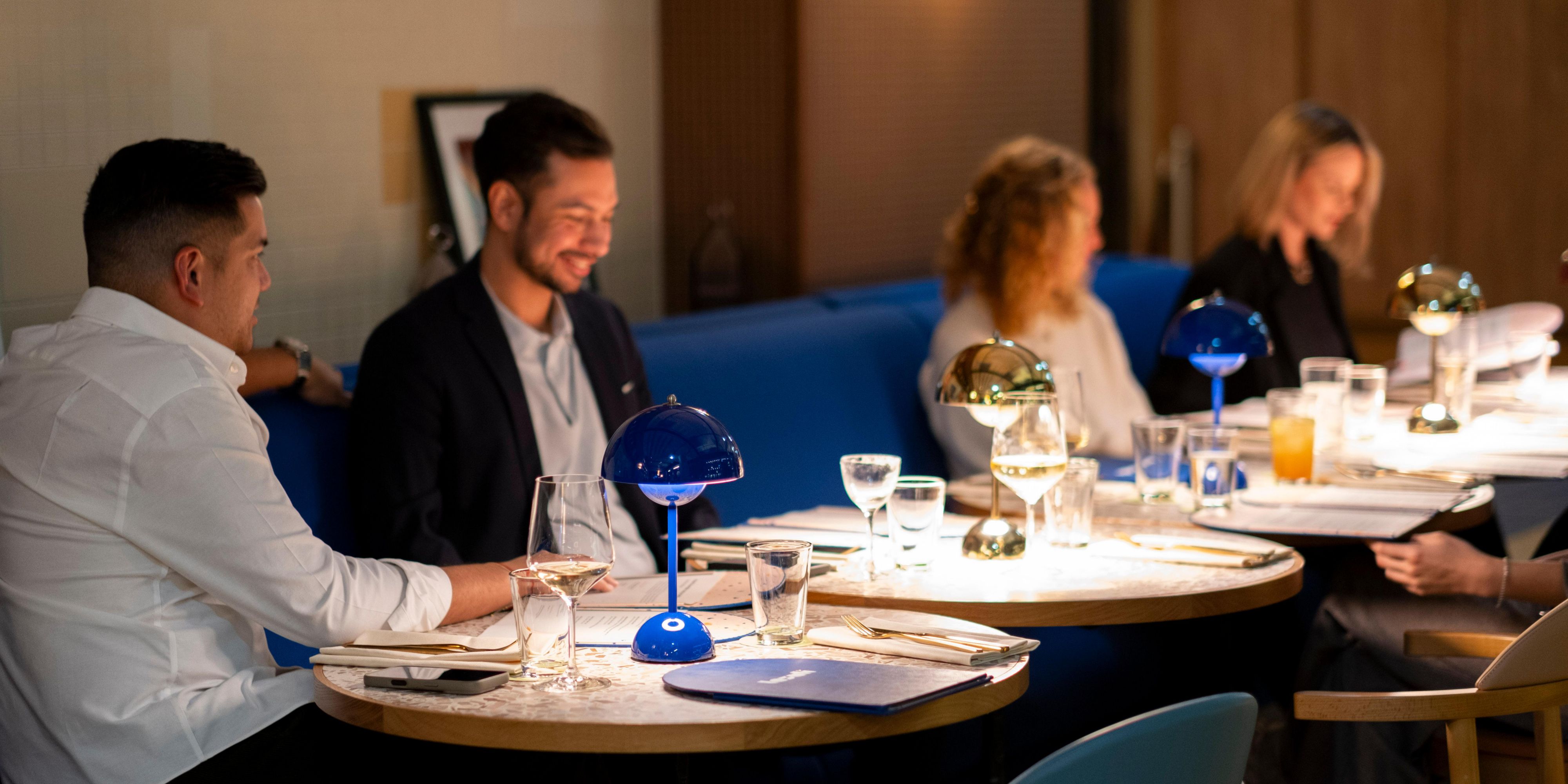 mehrere Gäste, die im Lazuli speisen, sitzen auf elektrischen blauen Nischen