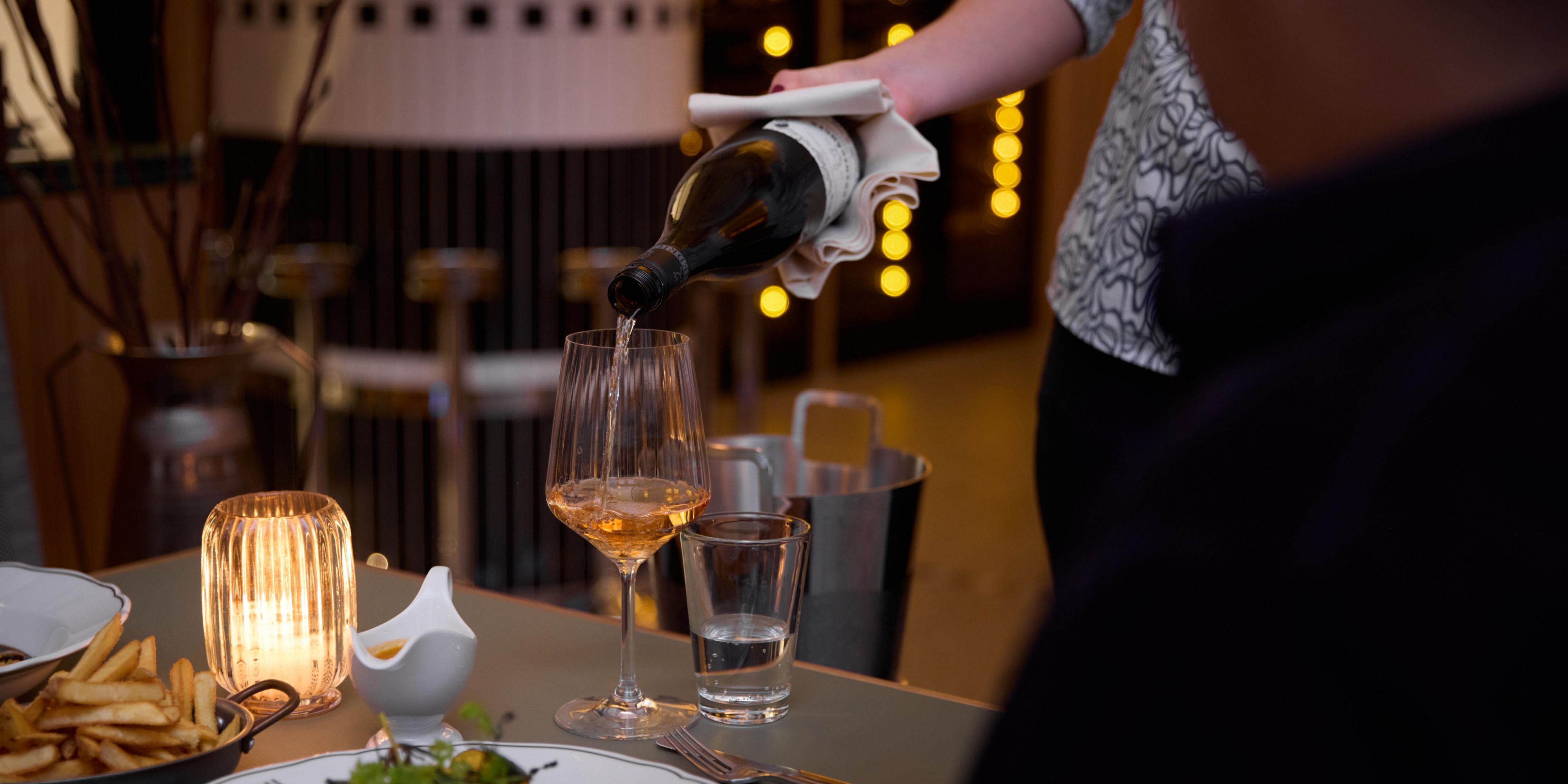 waiter pouring a glass of rose for dinner guest