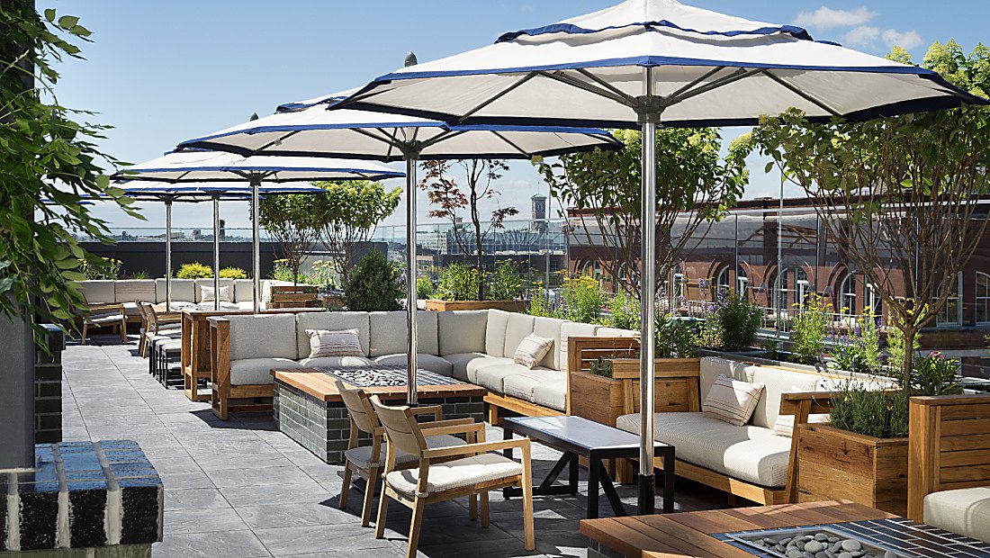 sun-drenched balcony lounge area with firepits and shade umbrellas