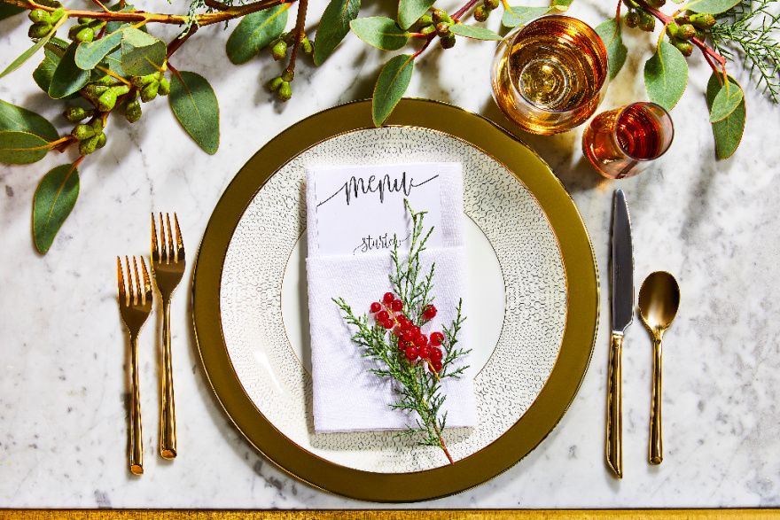 overhead view of a formal table setting with holiday greens and gold accents