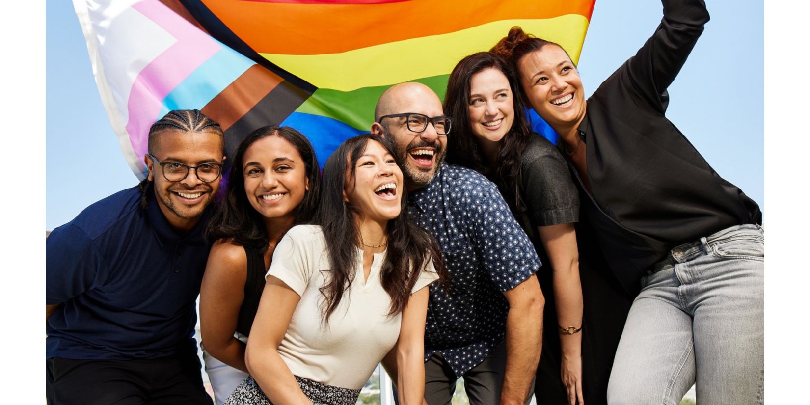 people smiling and holding a rainbow flag