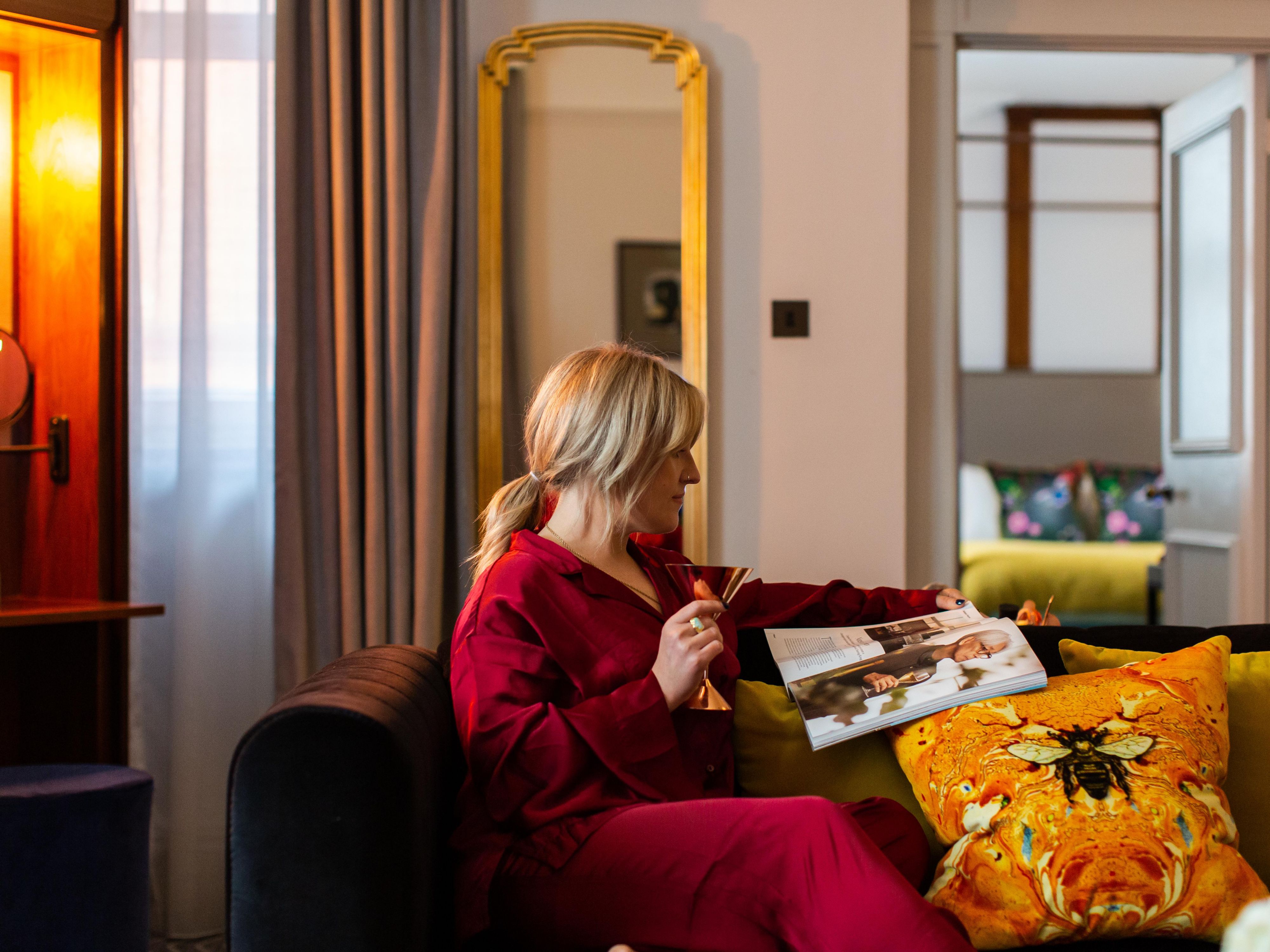A woman reading a magazine on the sofa in a luxury hotel guest room