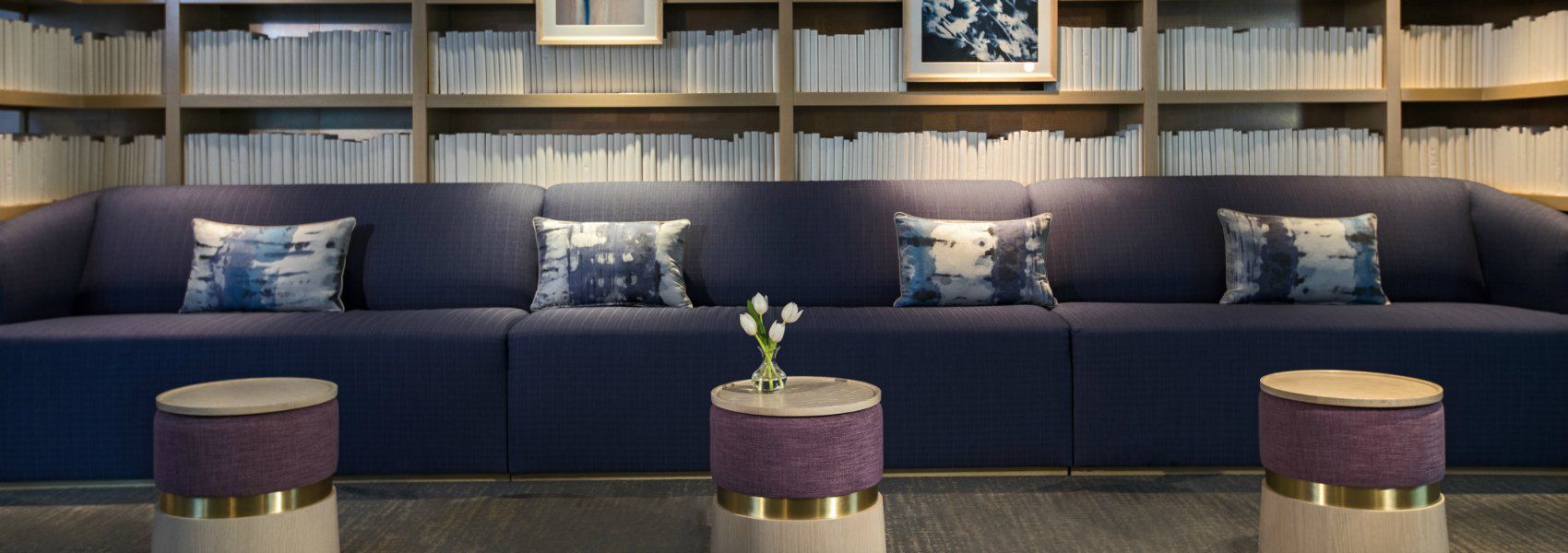 triple wide purple couch in front of a wall to wall bookshelf with white books