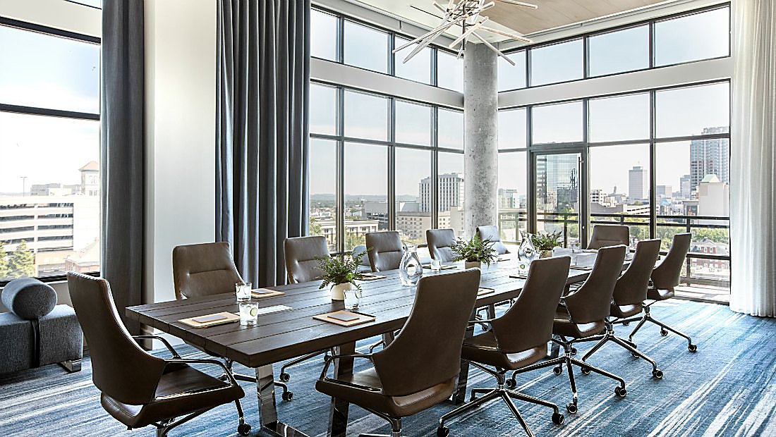 Rectangular meeting table with floor to ceiling windows in corner meeting room