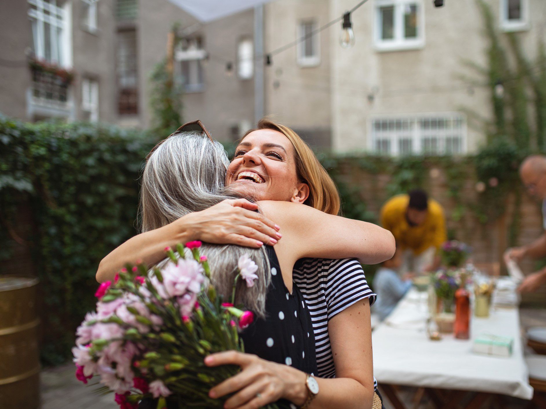 A daughter hugging her mother with flowers