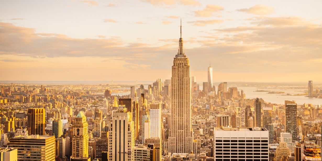 new youk city skyline at sunset looking at empire state building and river beyond