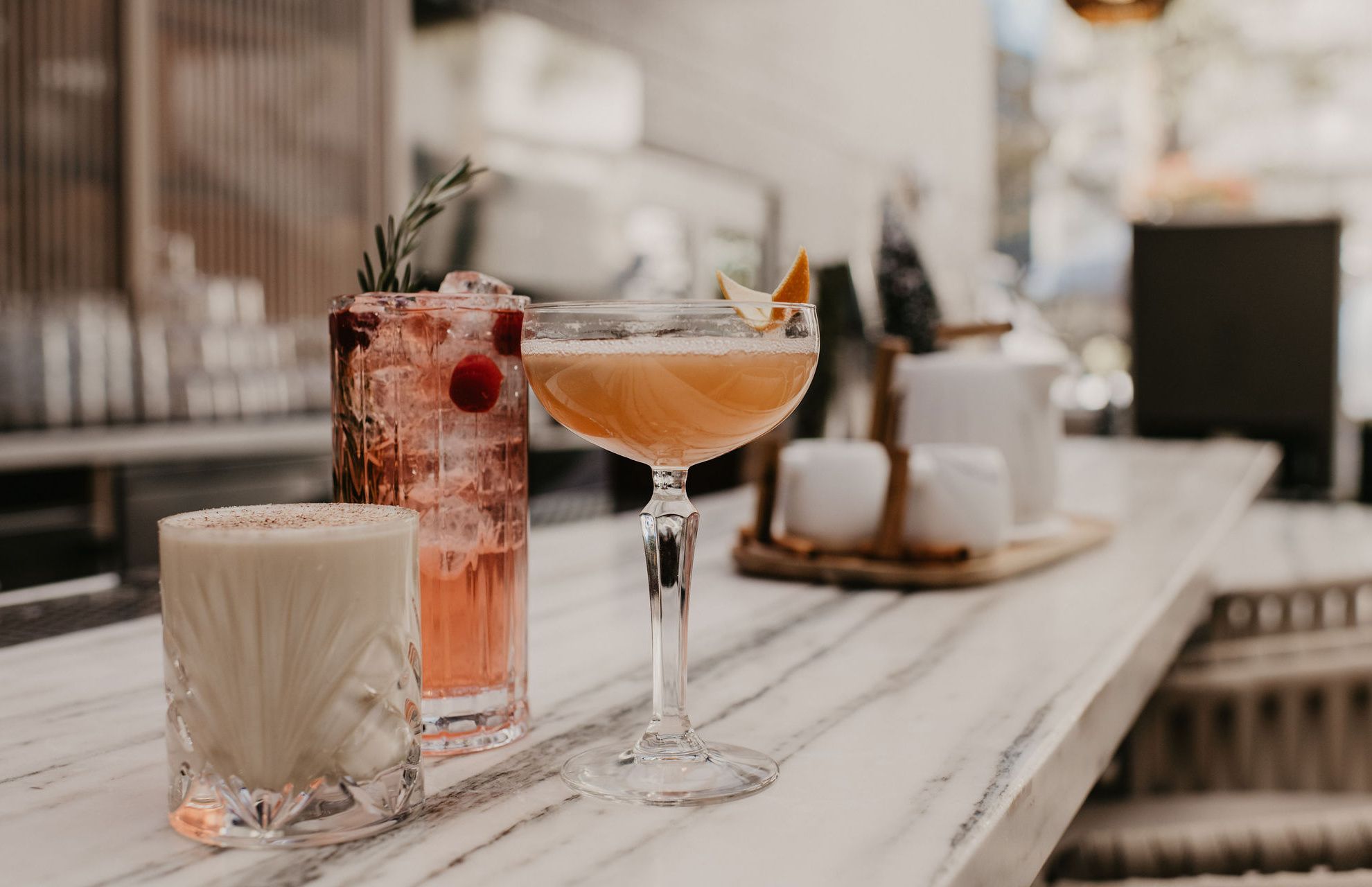Three beautiful cocktails with colorful garnishes on an outdoor bartop