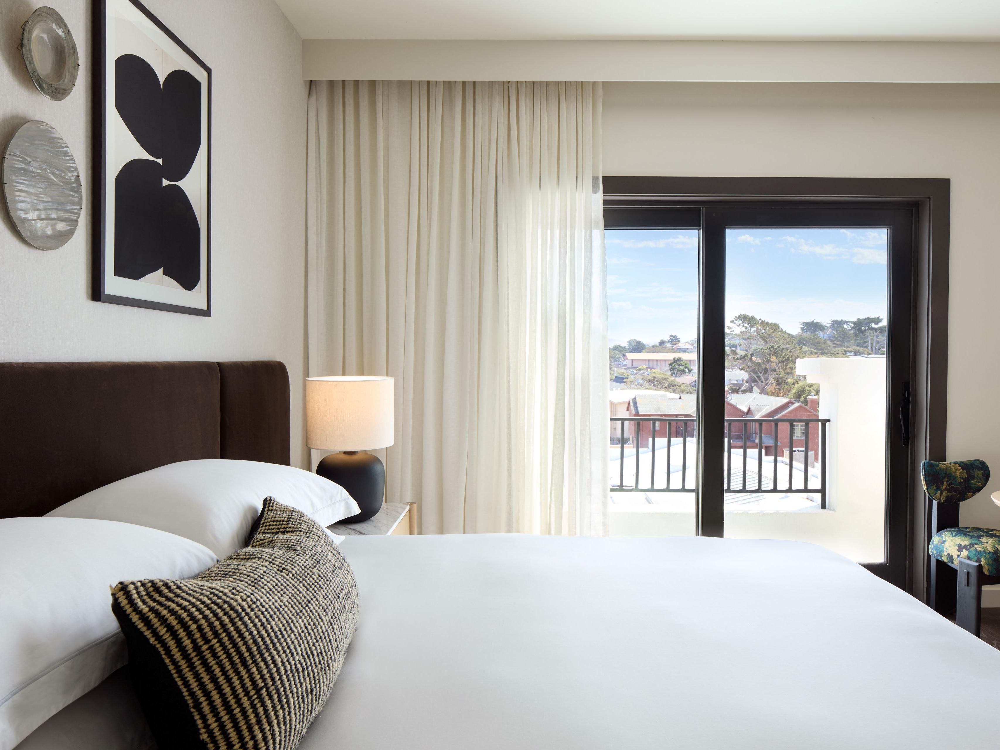 Elegant Pacific Grove guestroom with balcony and natural light.