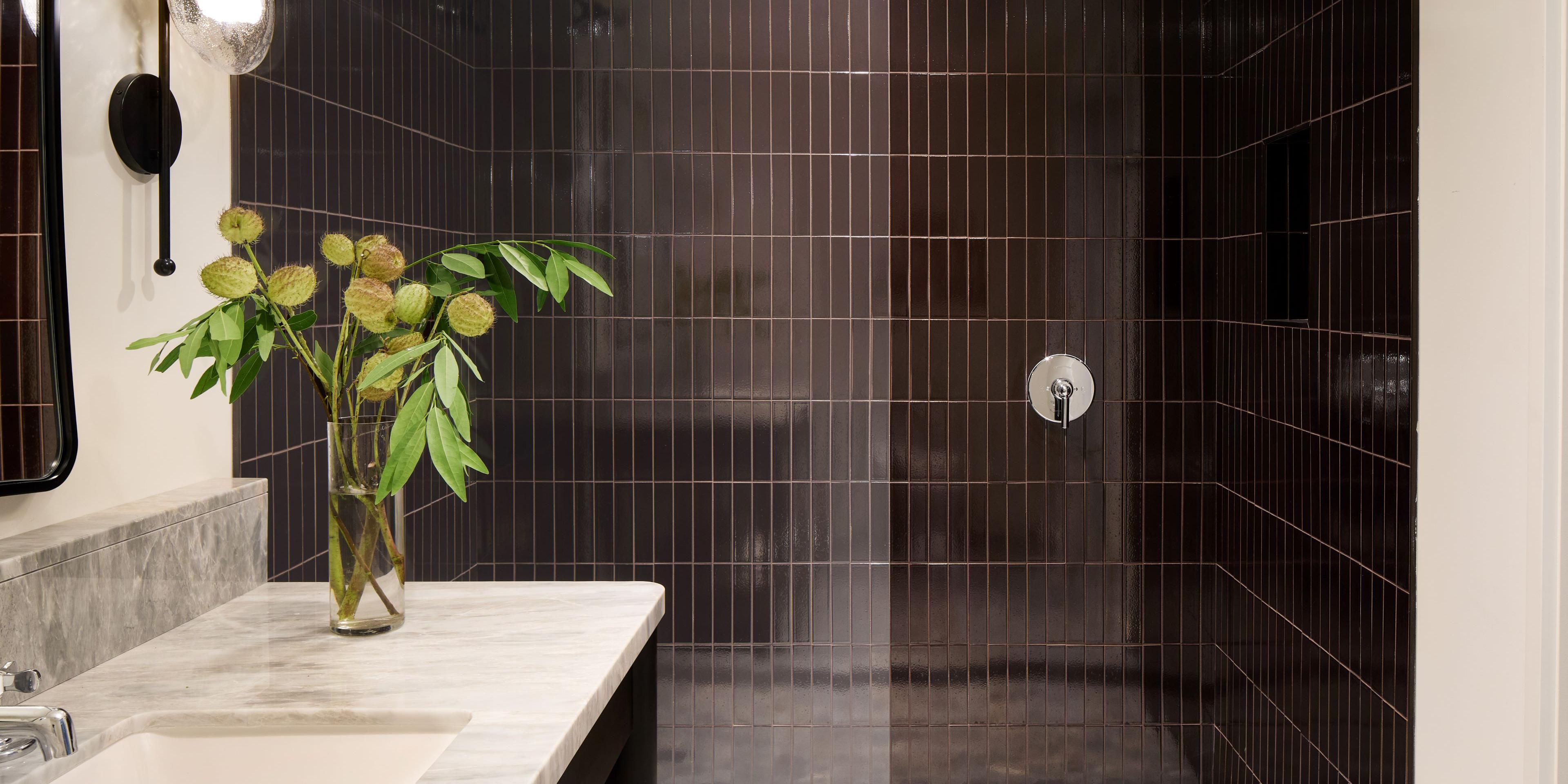 Marble countertop, modern fixtures, and elegant dark tile showers.