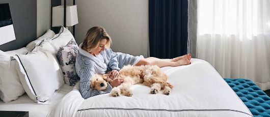 A woman and her dog cuddling on the bed