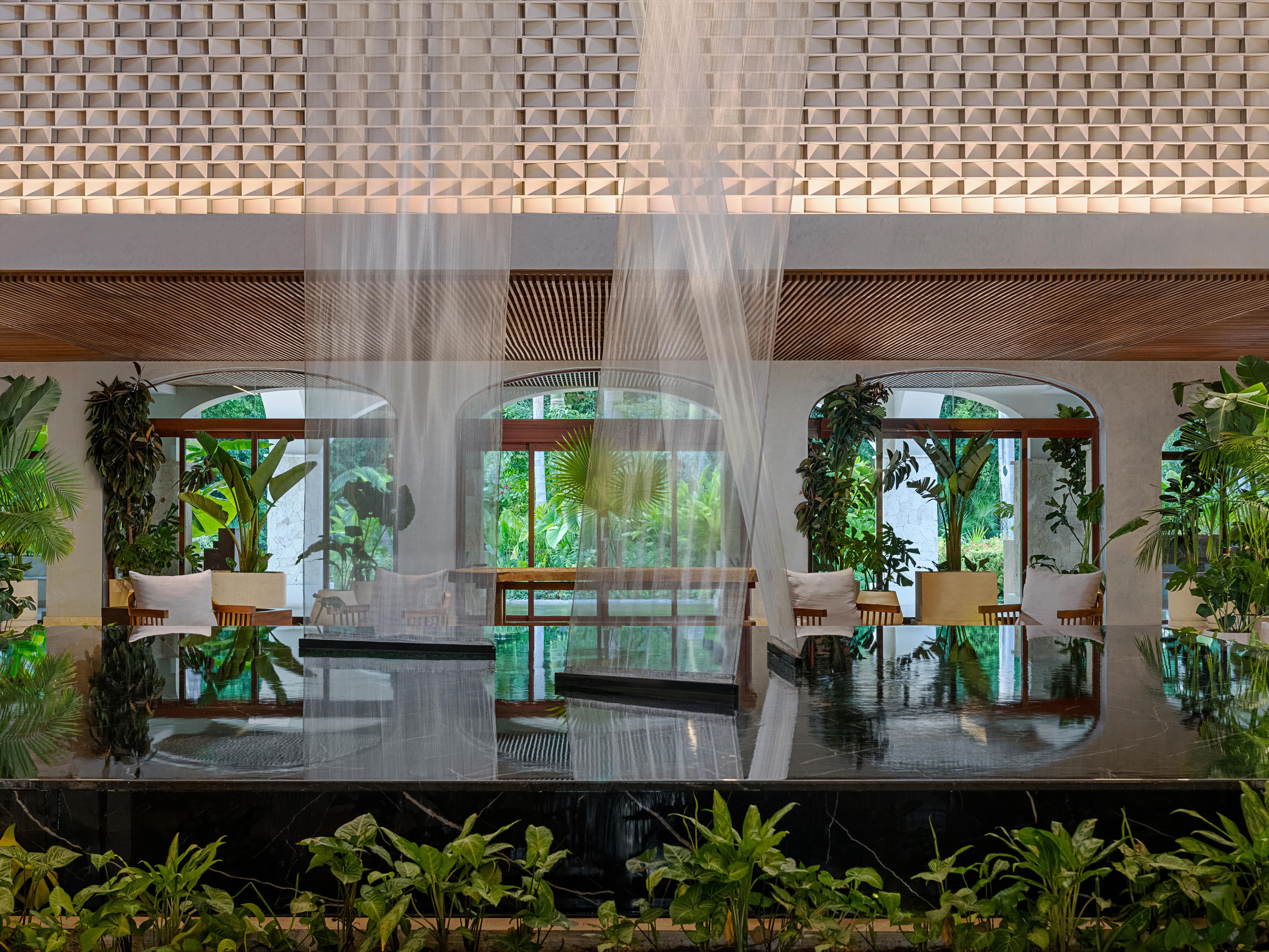 Open-air hotel lobby with hanging art and tropical greenery