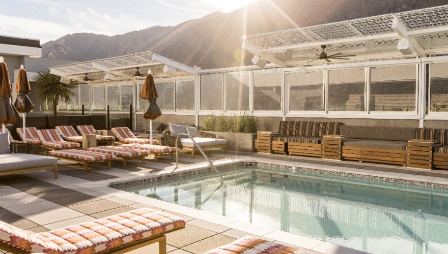 sunny pool deck with white lounge chairs and a desert mountain backdrop
