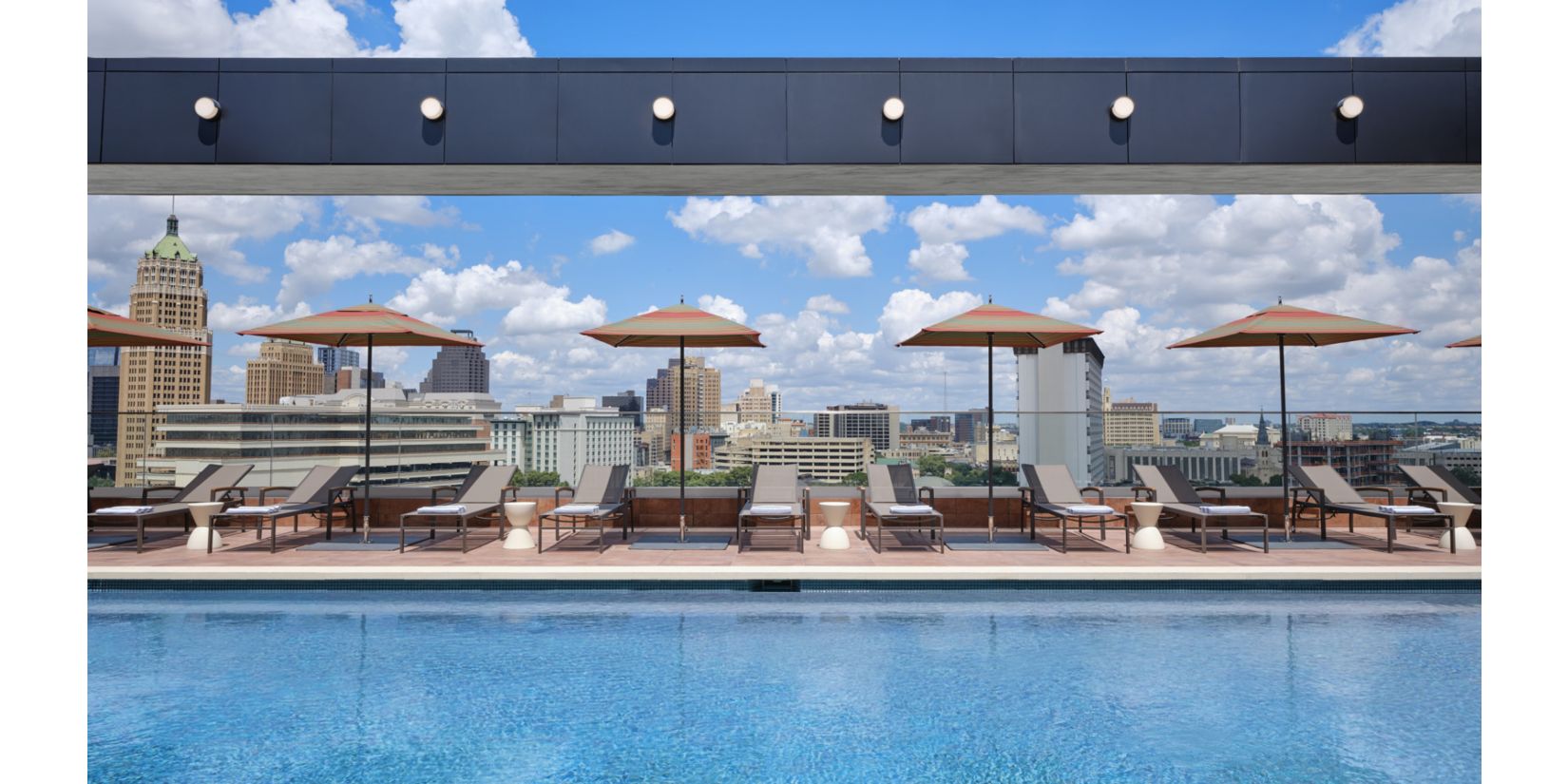 Rooftop pool with lounge chairs and umbrellas