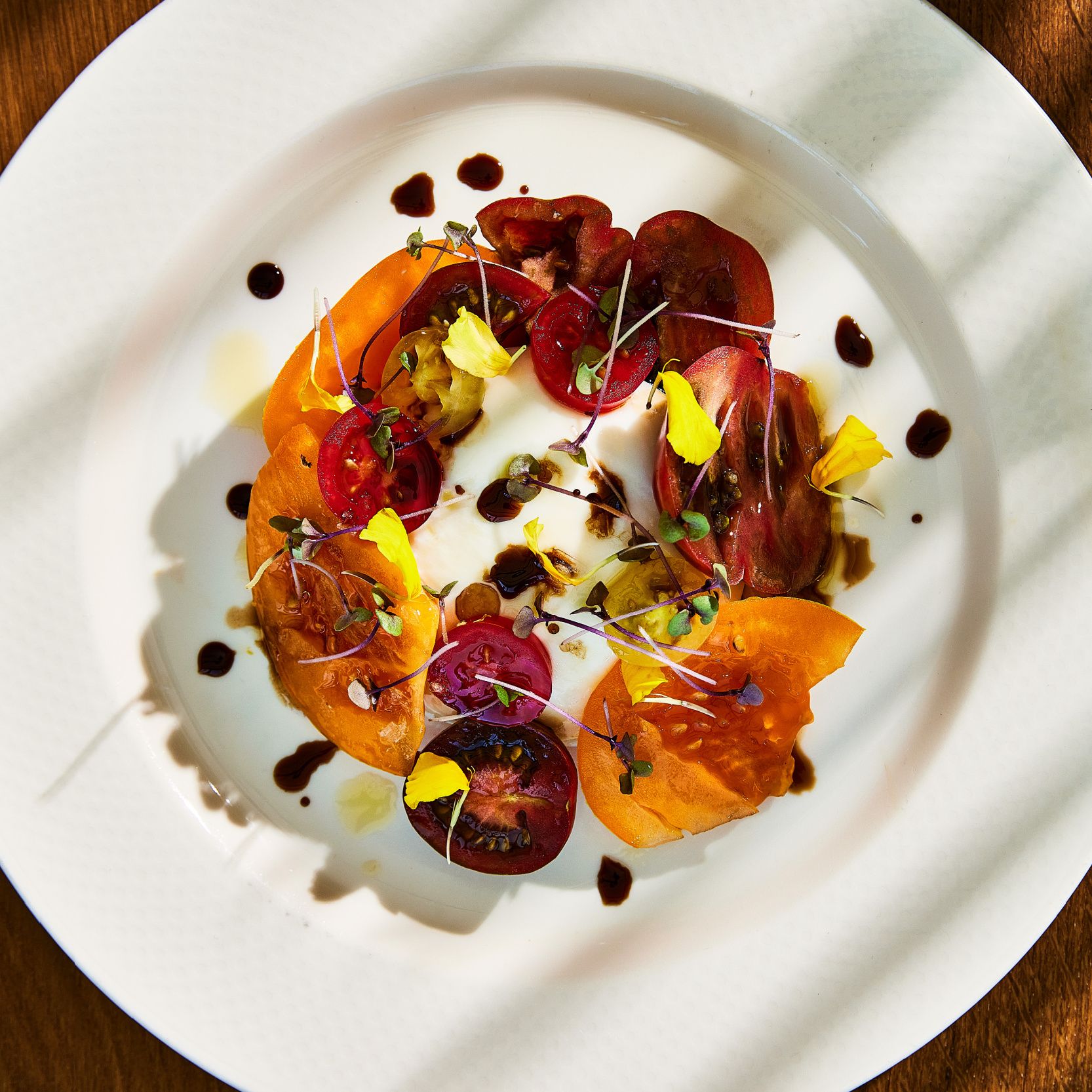 cà chua thái lát màu đậm xung quanh burrata trên chiếc đĩa màu trắng