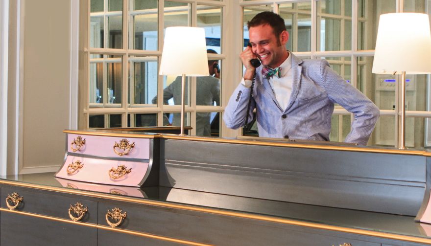 man in a suit smiling on the phone at reception desk