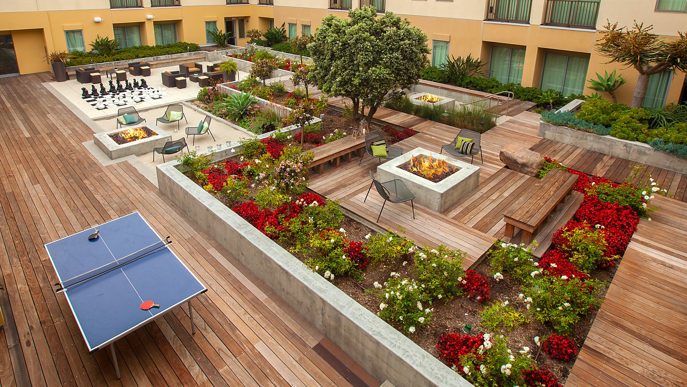 outdoor hotel courtyard with firepits, a ping pong table, and giant chessboard