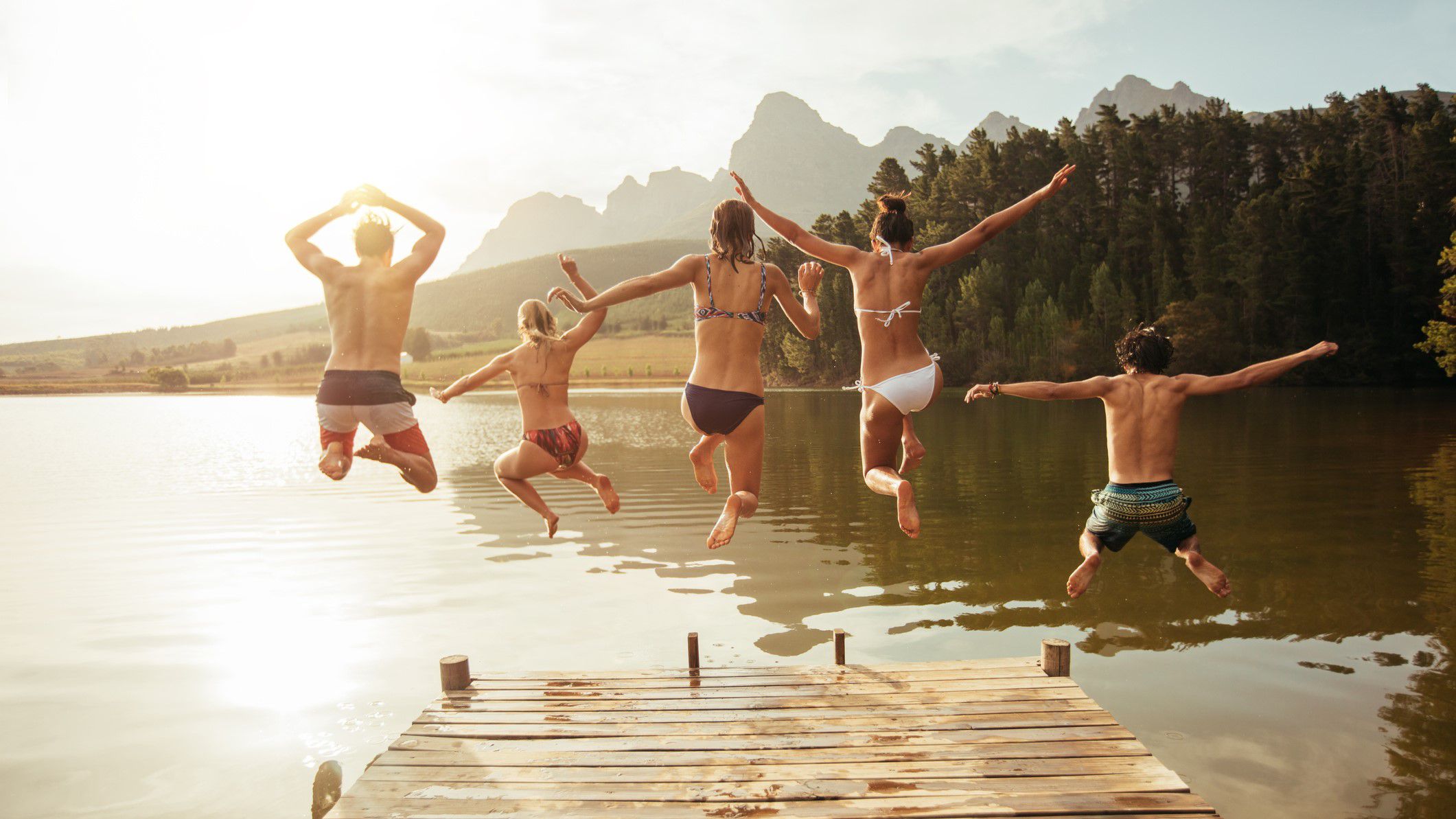 Friends jumping from jetty into lake