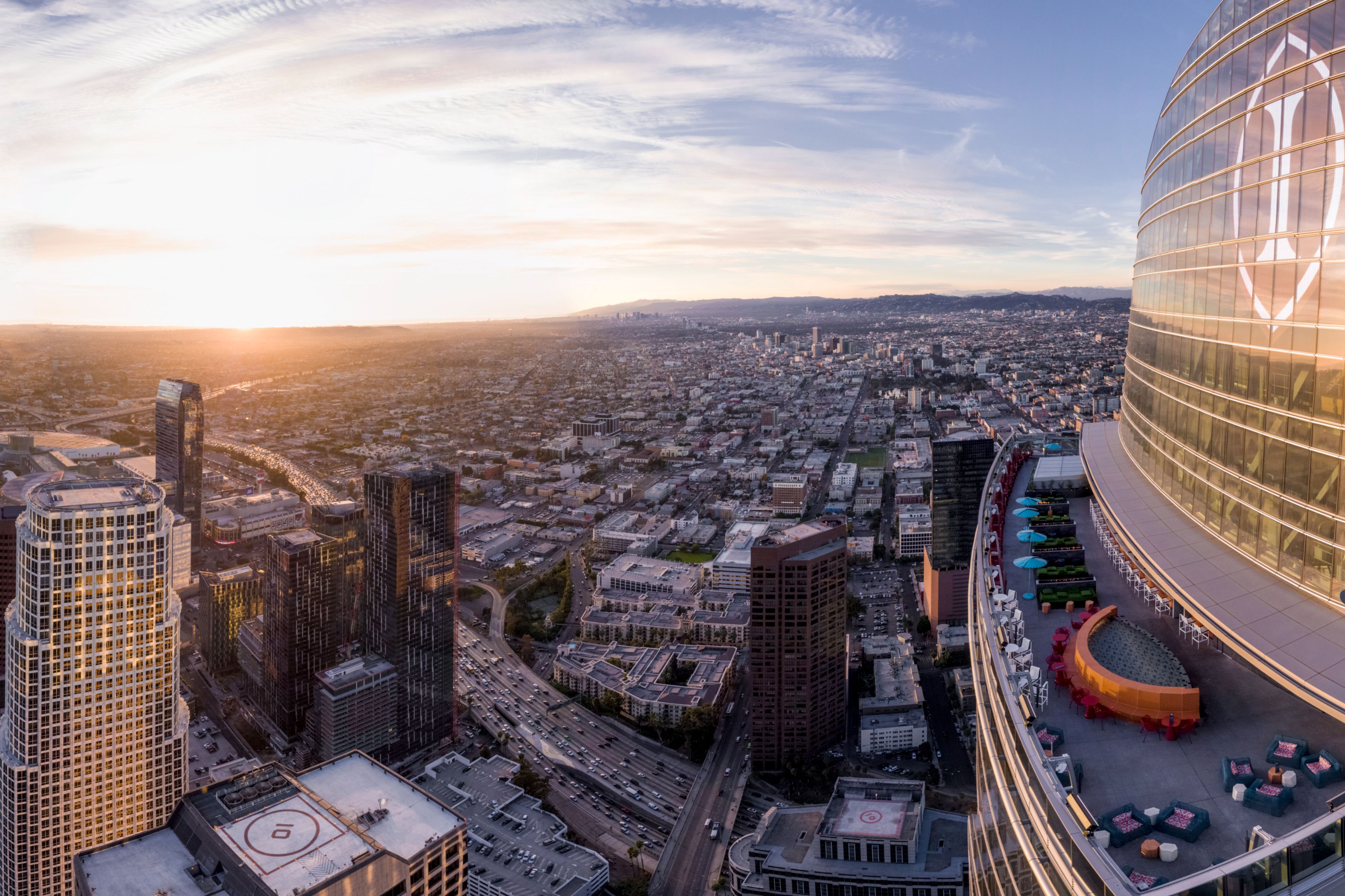 Panoramic view of downtown Los Angeles Downtown at sunset from InterContinental Los Angeles, featuring the hotel's exterior terrace, surrounding skyscrapers, and sprawling city skyline.