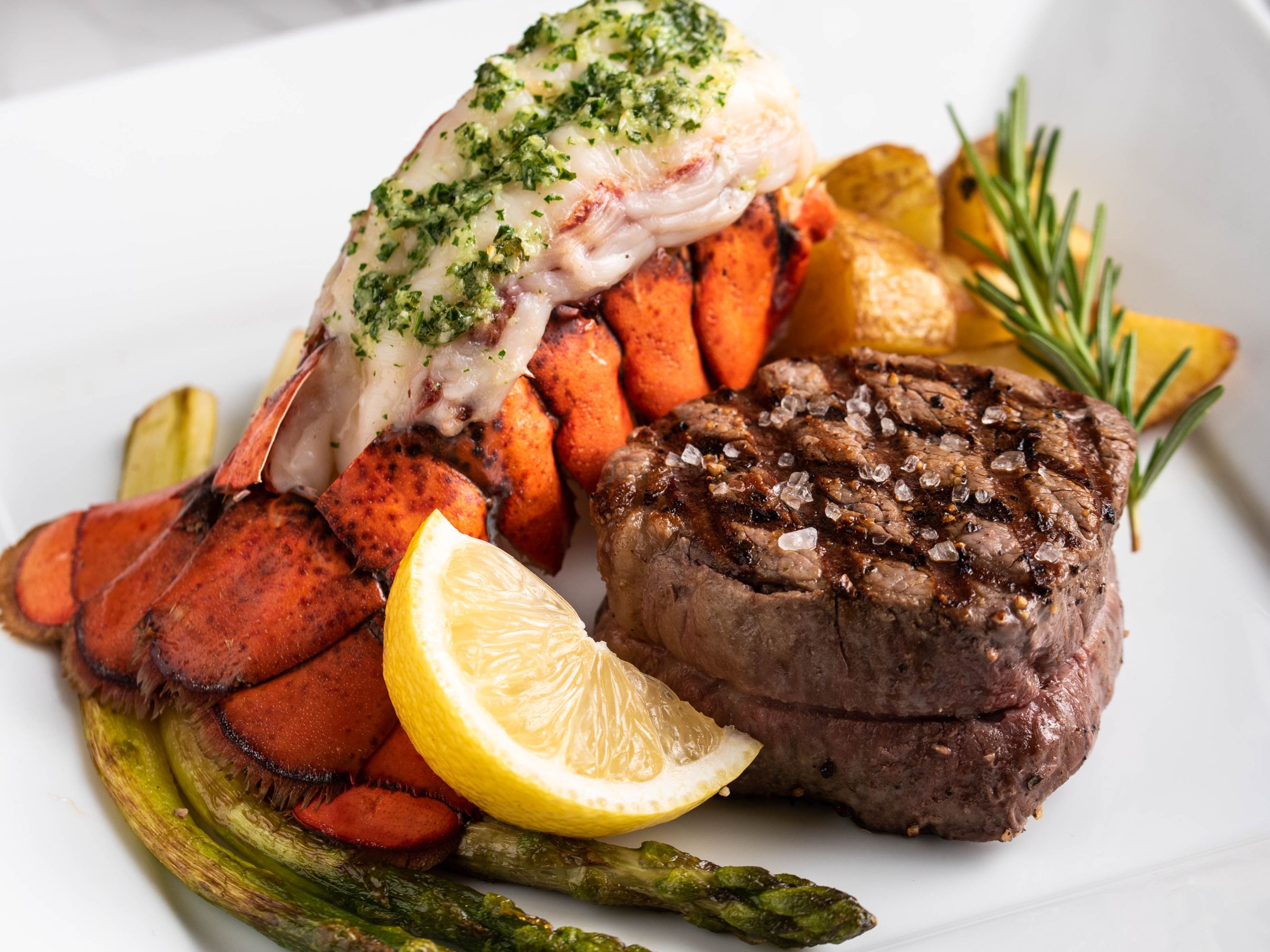 Lobster and steak dinner with asparagus.
