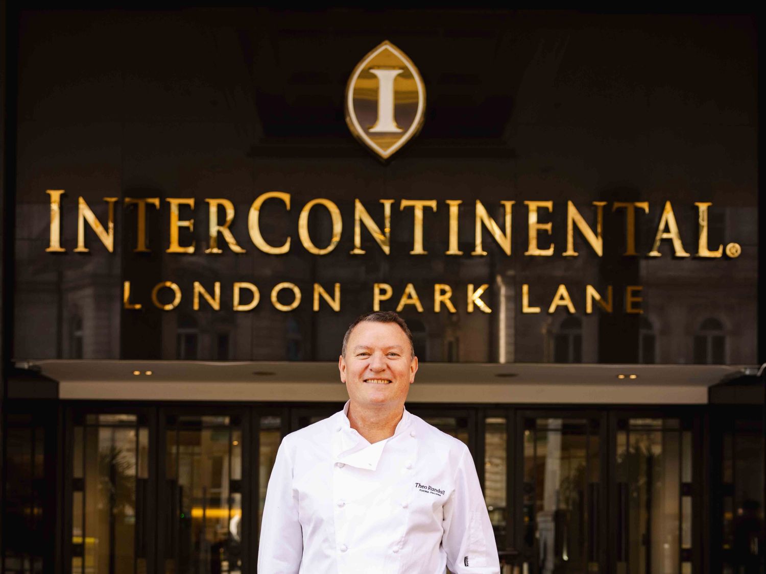 Theo Randall standing outside hotel entrance smiling