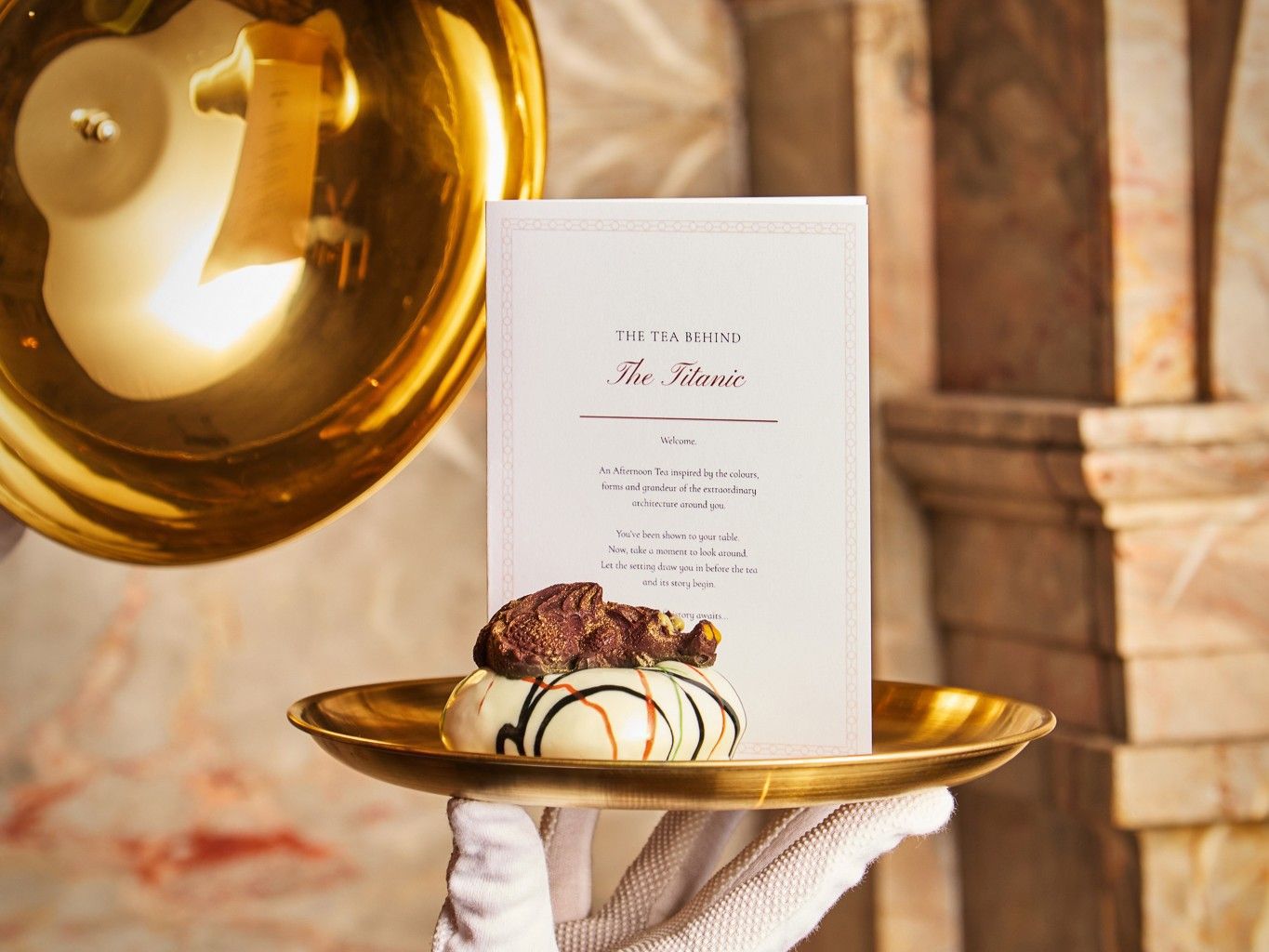dessert held up on a plate with the titanic afternoon tea menu on display