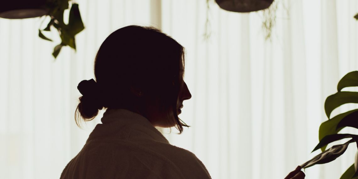 Silhouetted woman with hanging plants