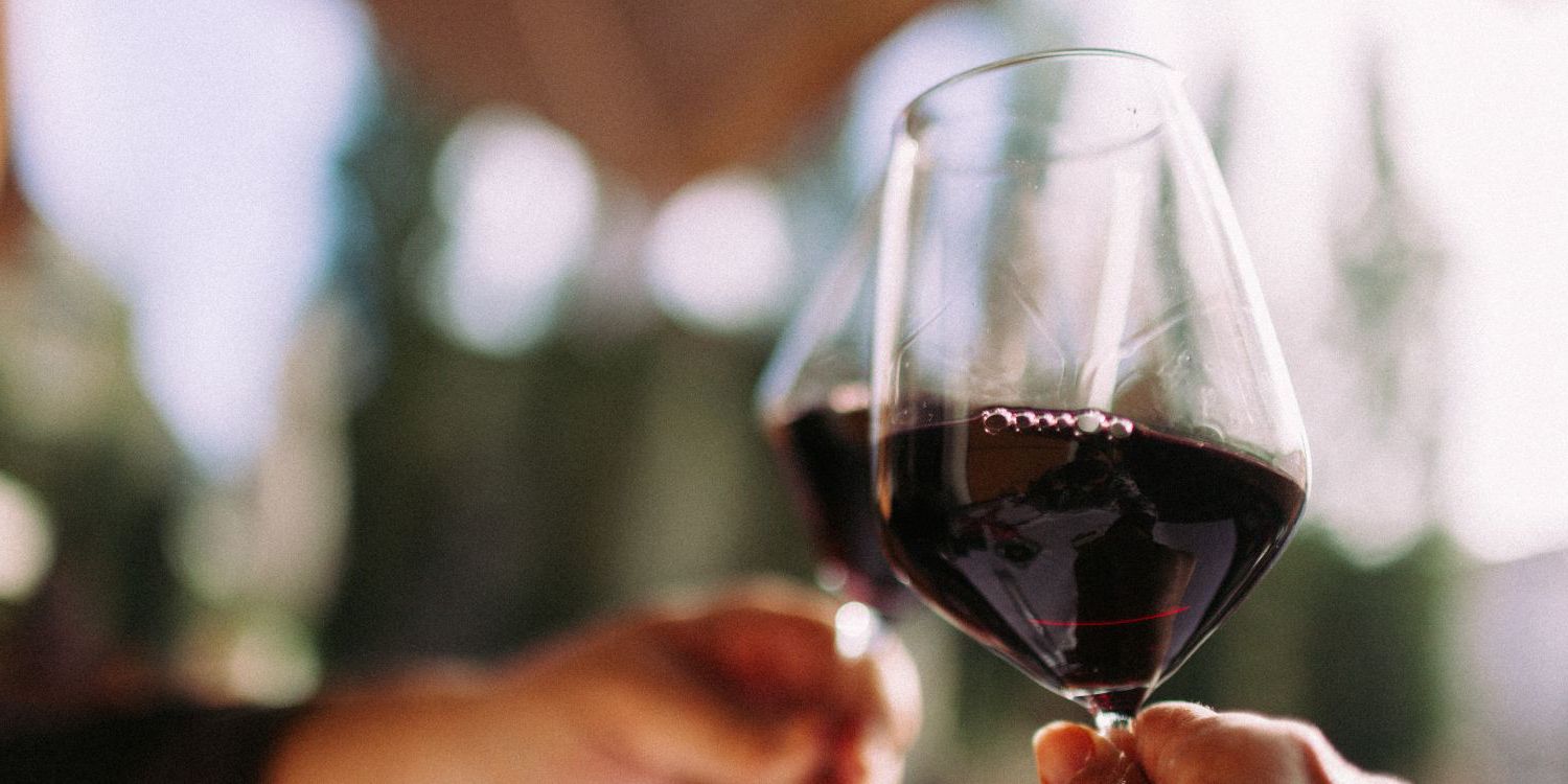 two people cheersing their red wine glasses