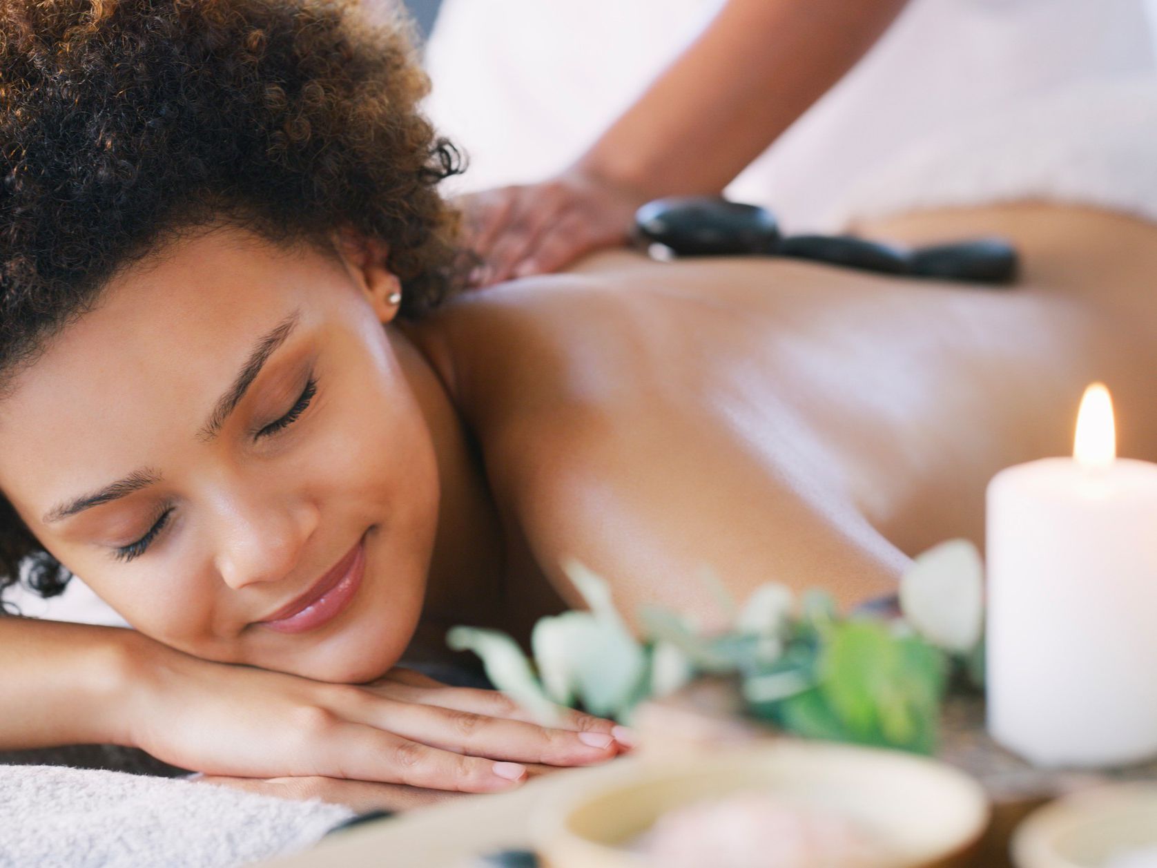 Spa therapist gently massaging a client’s head while they lie on a towel.