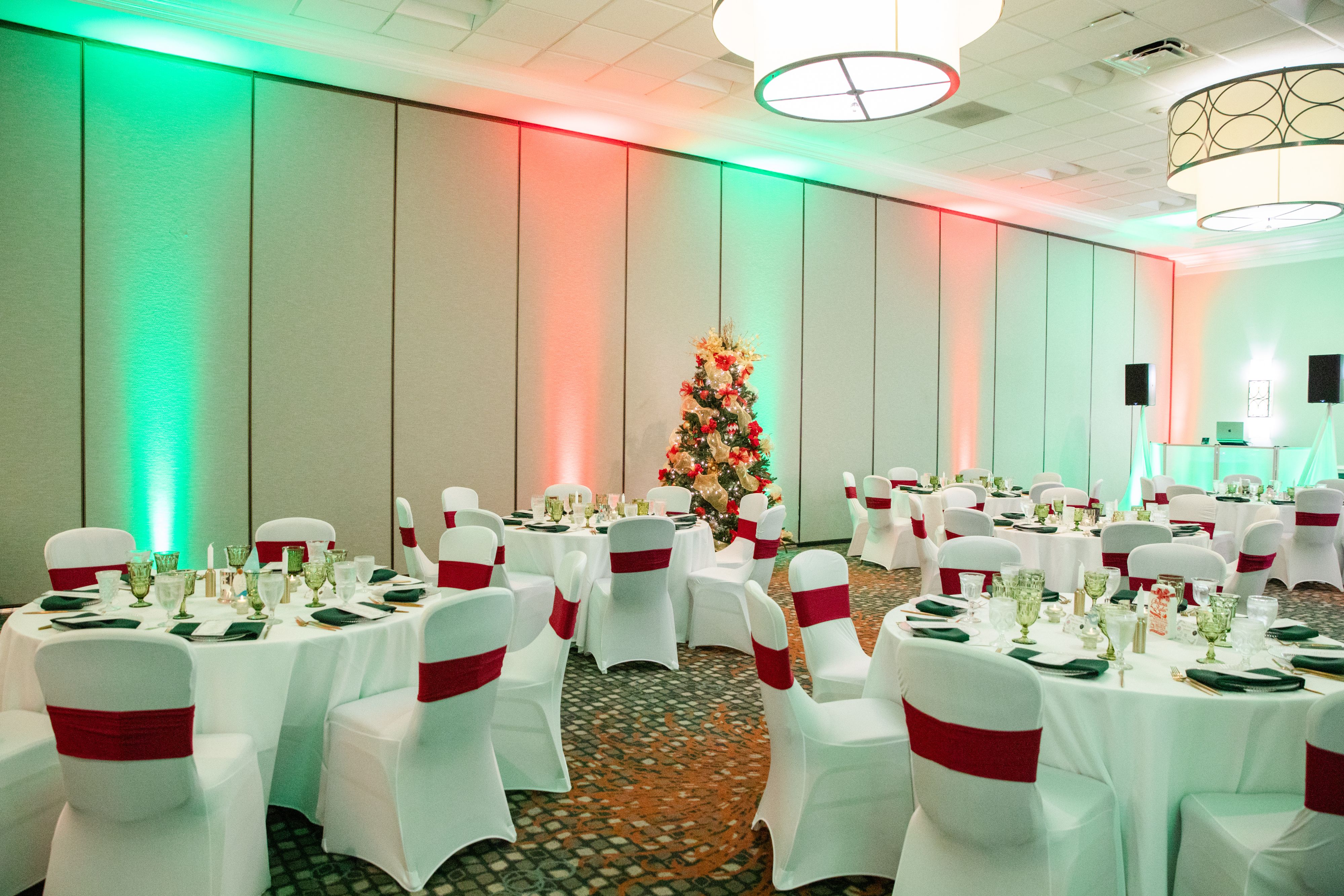 Holiday ballroom set for festive banquet with Christmas tree.