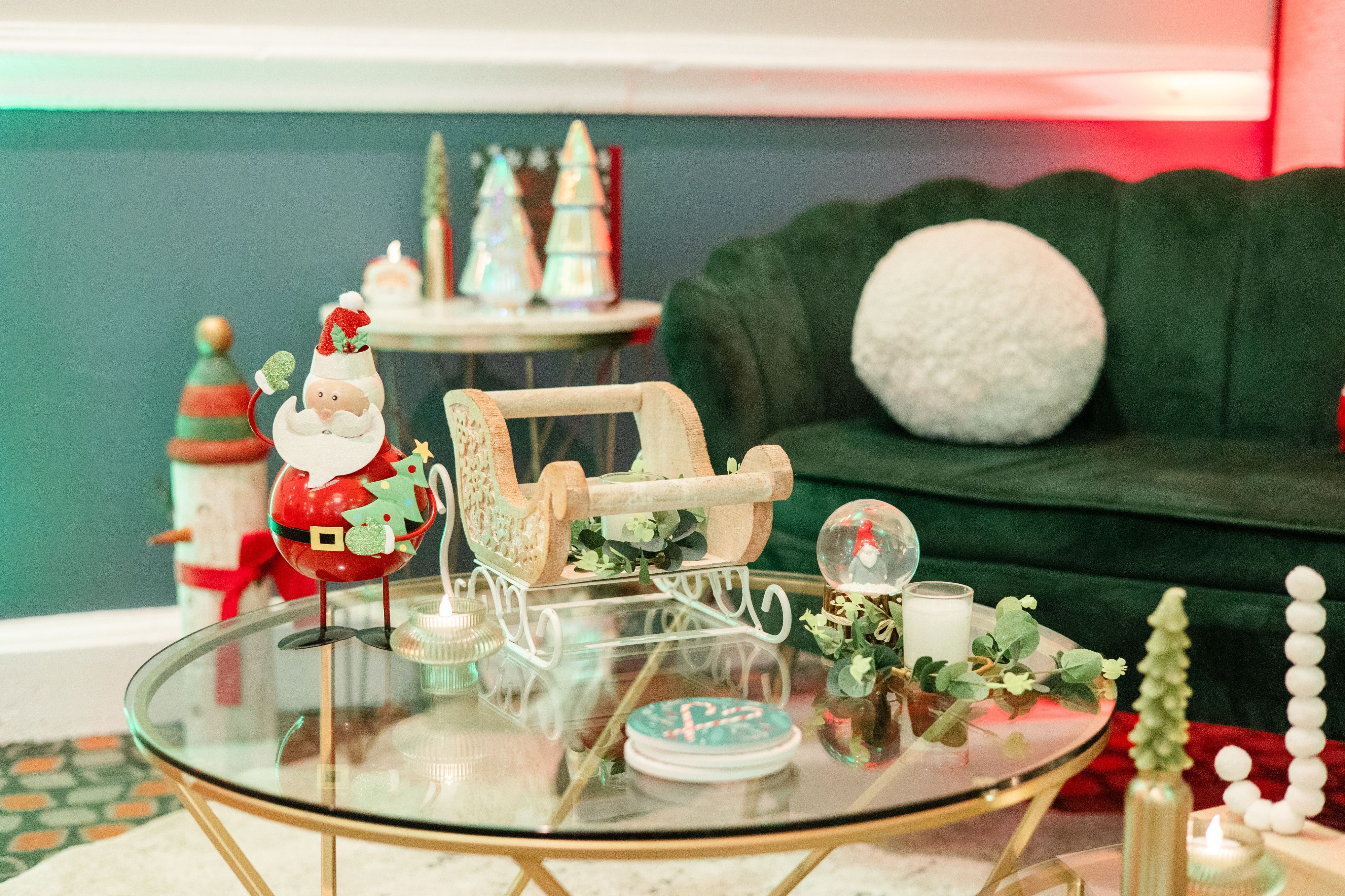 Santa figurine and holiday sled decor on glass coffee table.