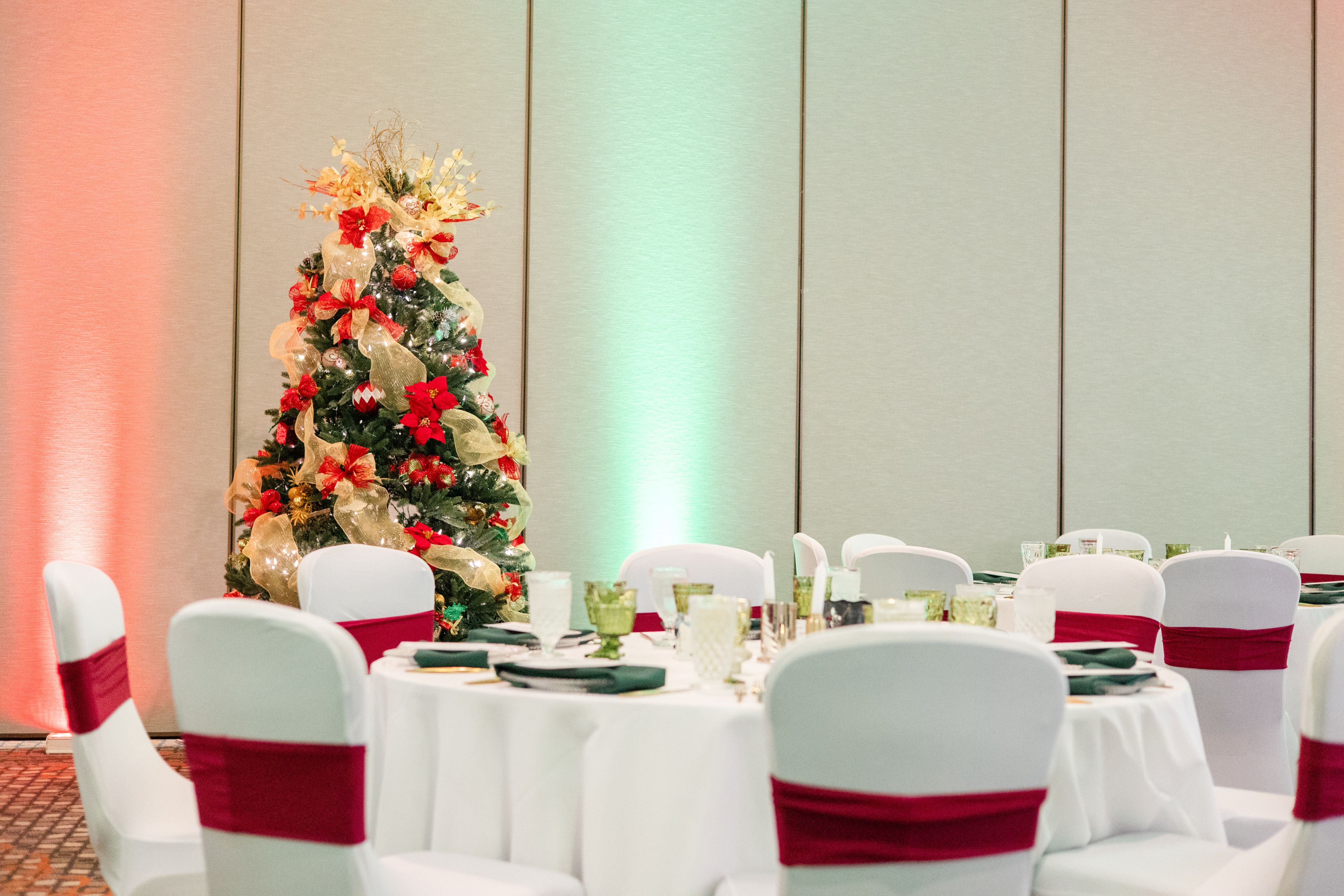 Formal holiday dinner table with Christmas tree in background.